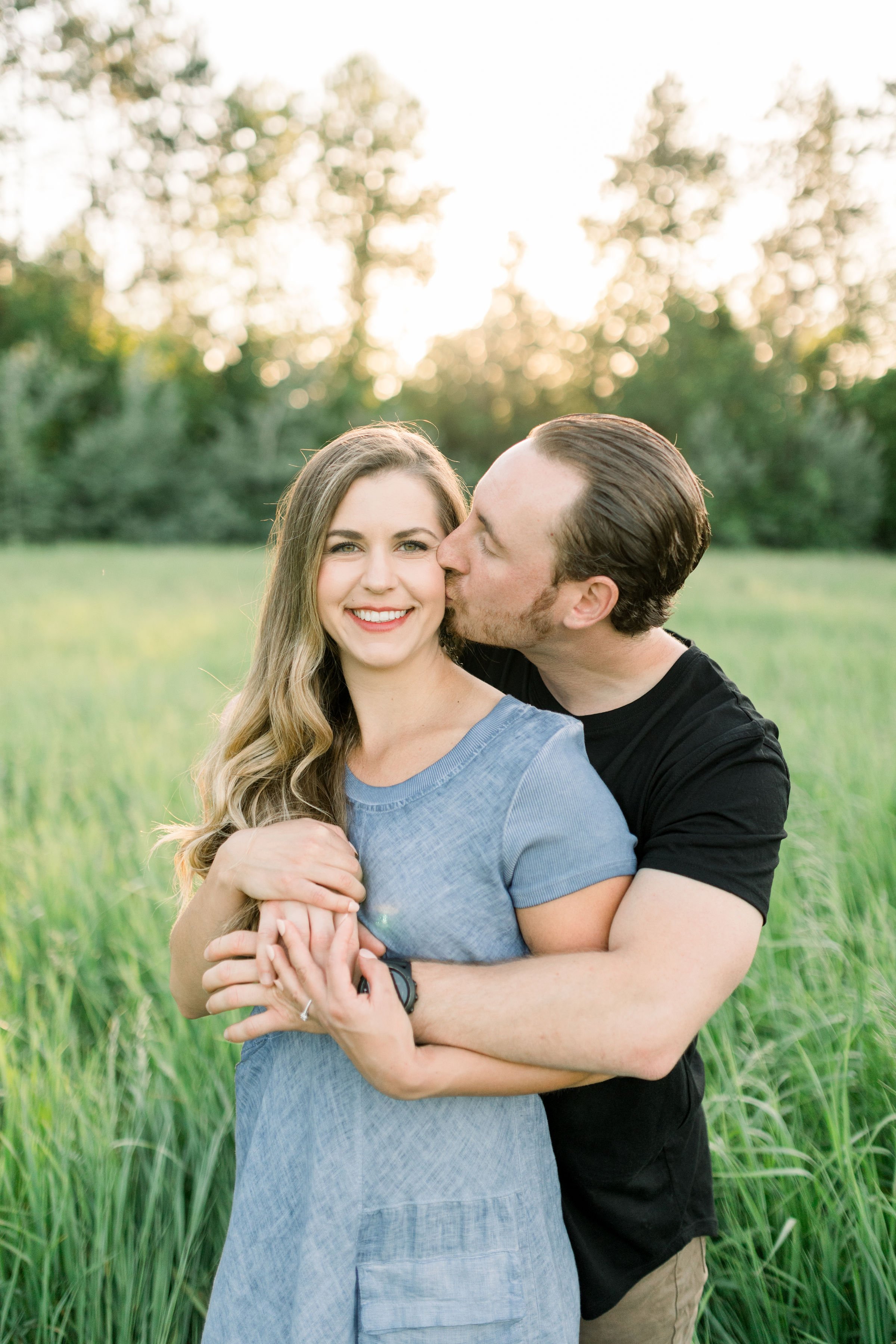  Engagement portrait with a woman looking forward as her fiance holds and kisses her by Chelsea Mason Photography. engagement inspo #chelseamasonphotography #chelseamasonengagements #Ottawaengagments #Almonteengagementphotographer #outdoorengagments 
