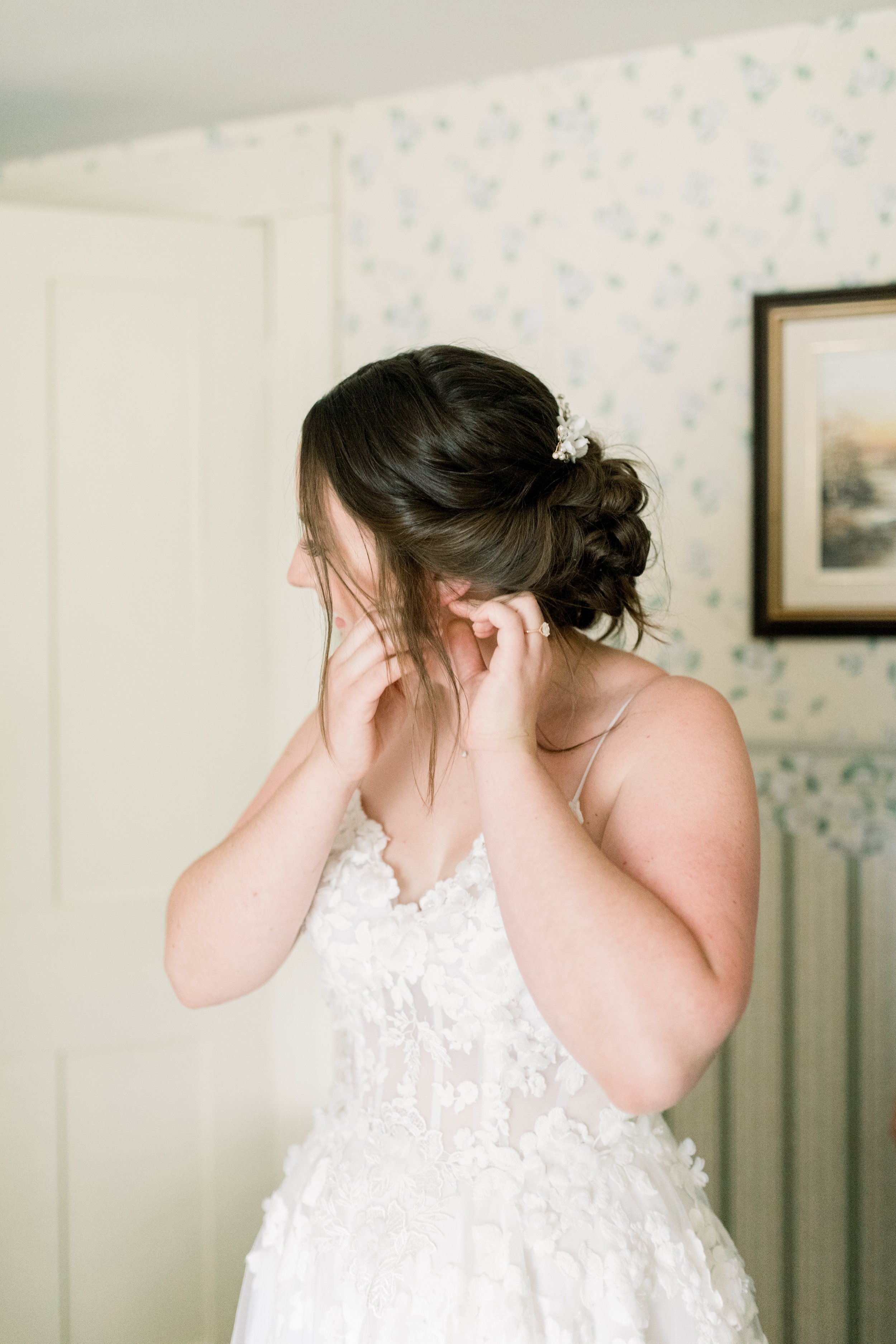  A bride putting in her earrings getting ready to walk down the aisle by Chelsea Mason Photography. bridal earrings getting ready #chelseamasonphotography #chelseamasonweddings #Ontarioweddings #Boulterweddingphotographer #laceweddinggown 