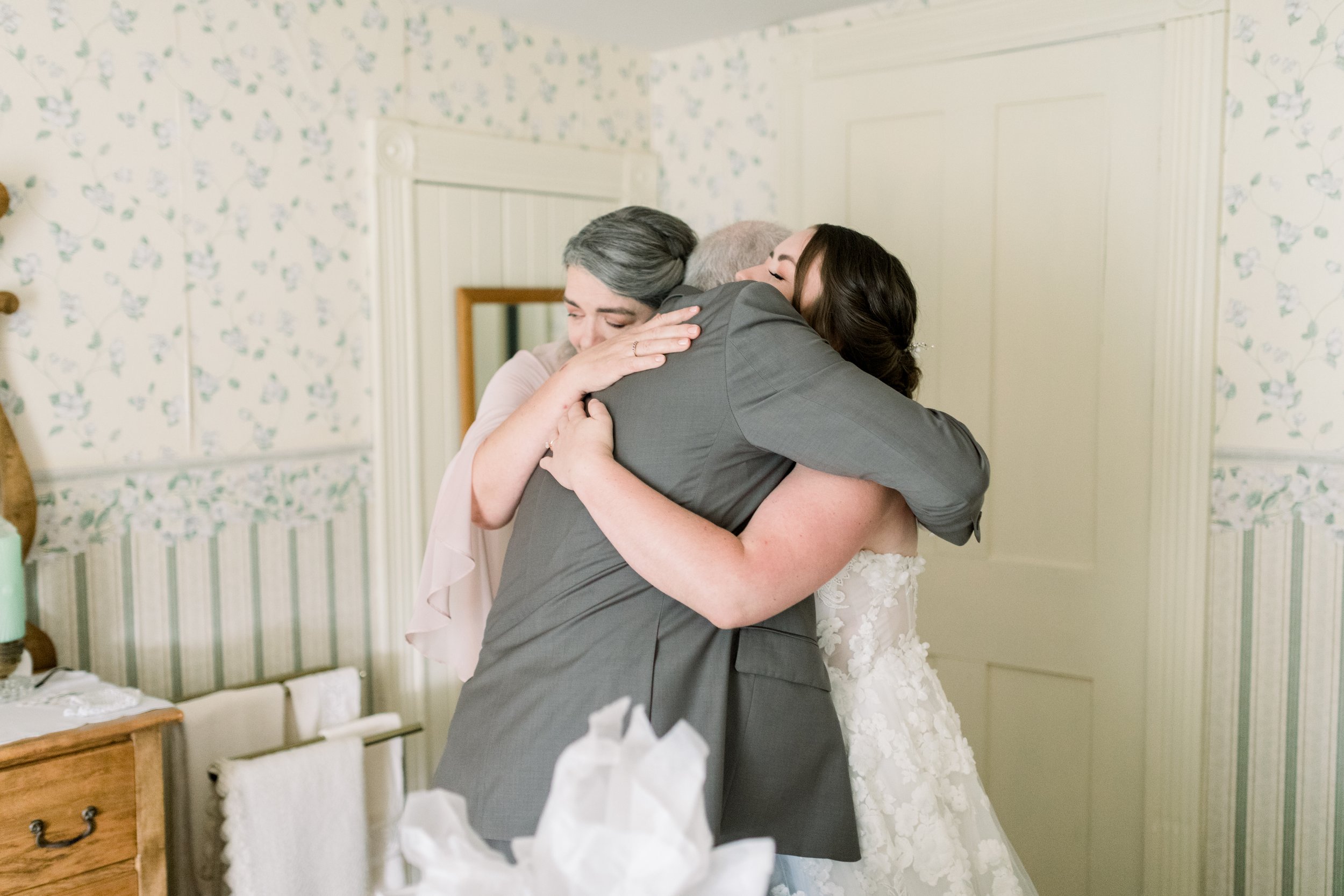  A bride spends a moment hugging her parents before the wedding by Chelsea Mason Photography in Boulter. family hug at wedding wedding moments #chelseamasonphotography #chelseamasonweddings #Ontarioweddings #Boulterweddingphotographer #laceweddinggow
