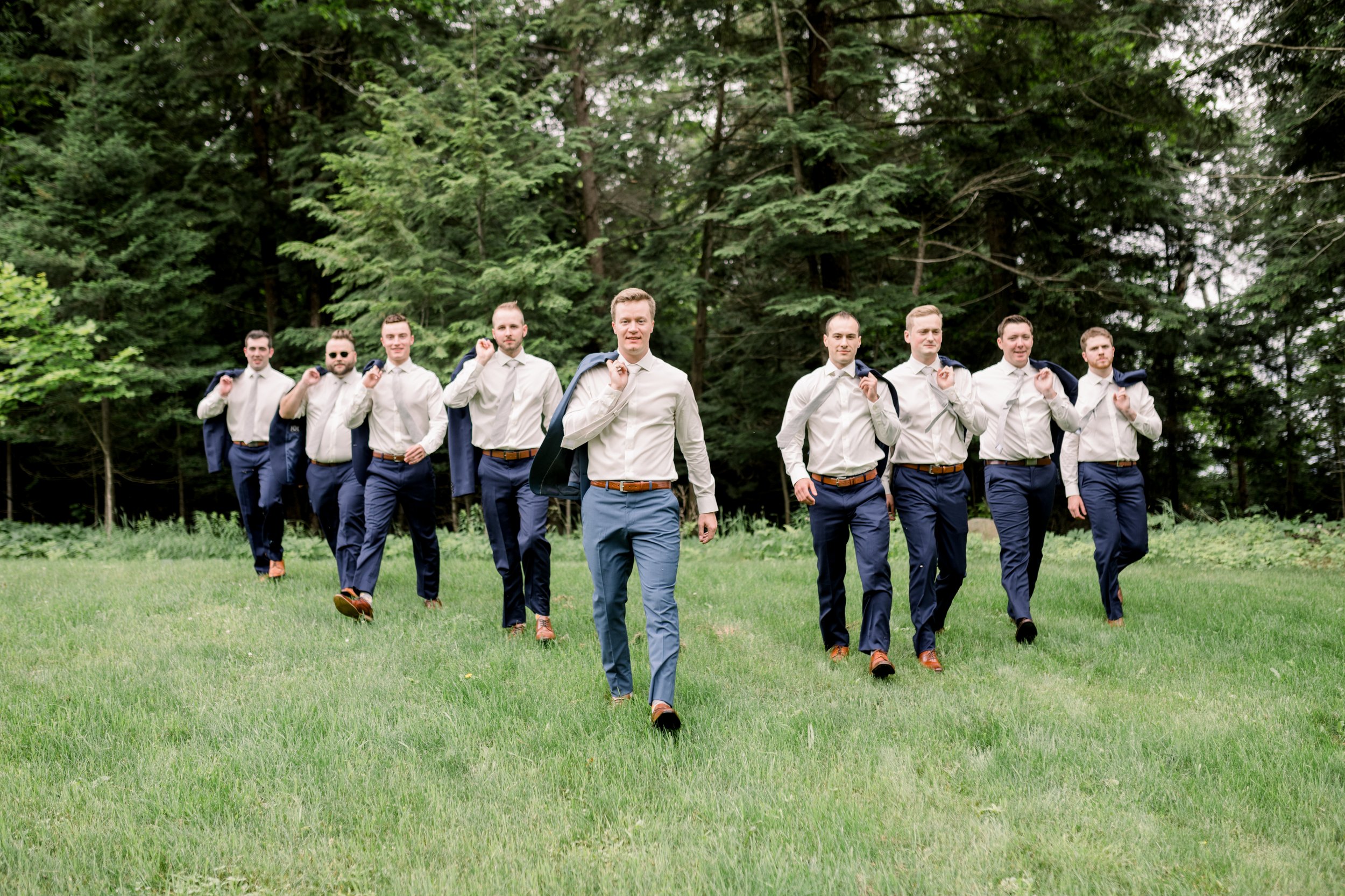  Groom and groomsmen walk with coats over their shoulders by Chelsea Mason Photography in Ontario. groomsmen style portrait blue suit #chelseamasonphotography #chelseamasonweddings #Ontarioweddings #Boulterweddingphotographer #laceweddinggown 