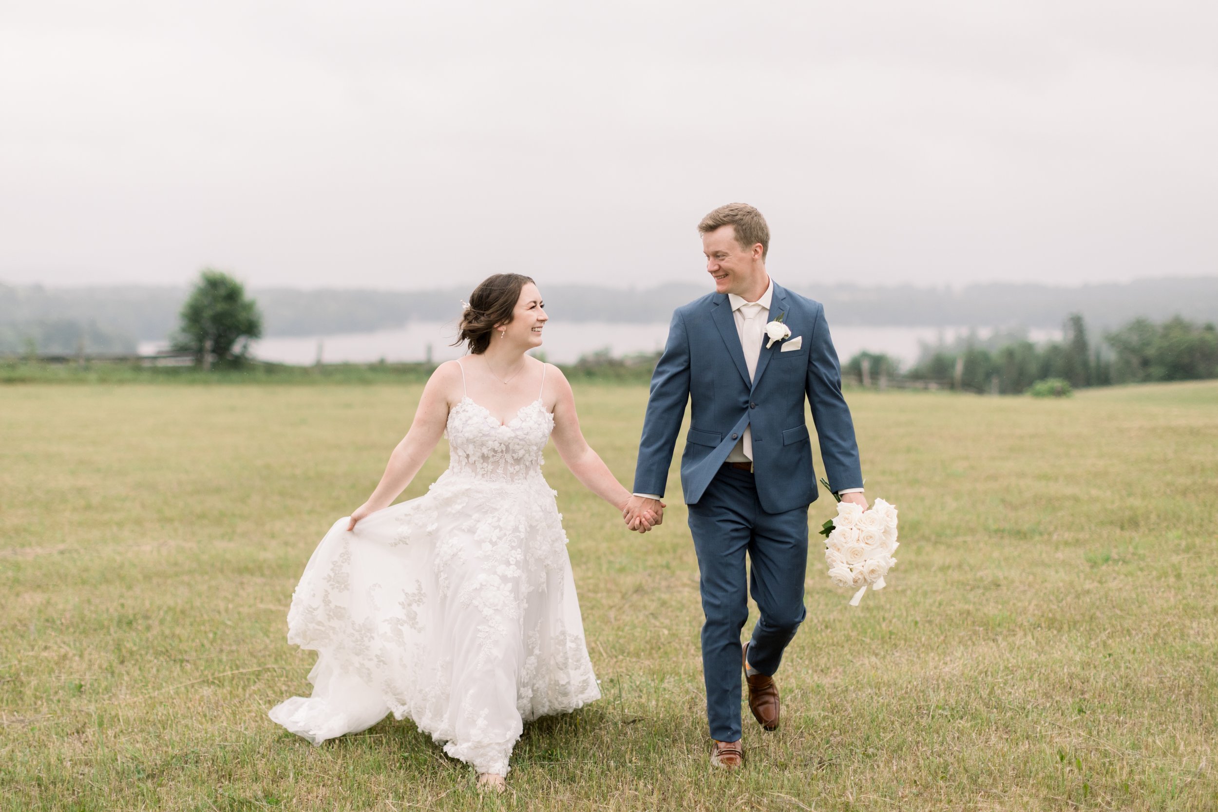  Newlyweds walking hand in hand in front of a lake captured by Chelsea Mason Photography Ontario wedding photographer. lace wedding dress #chelseamasonphotography #chelseamasonweddings #Ontarioweddings #Boulterweddingphotographer #laceweddinggown 