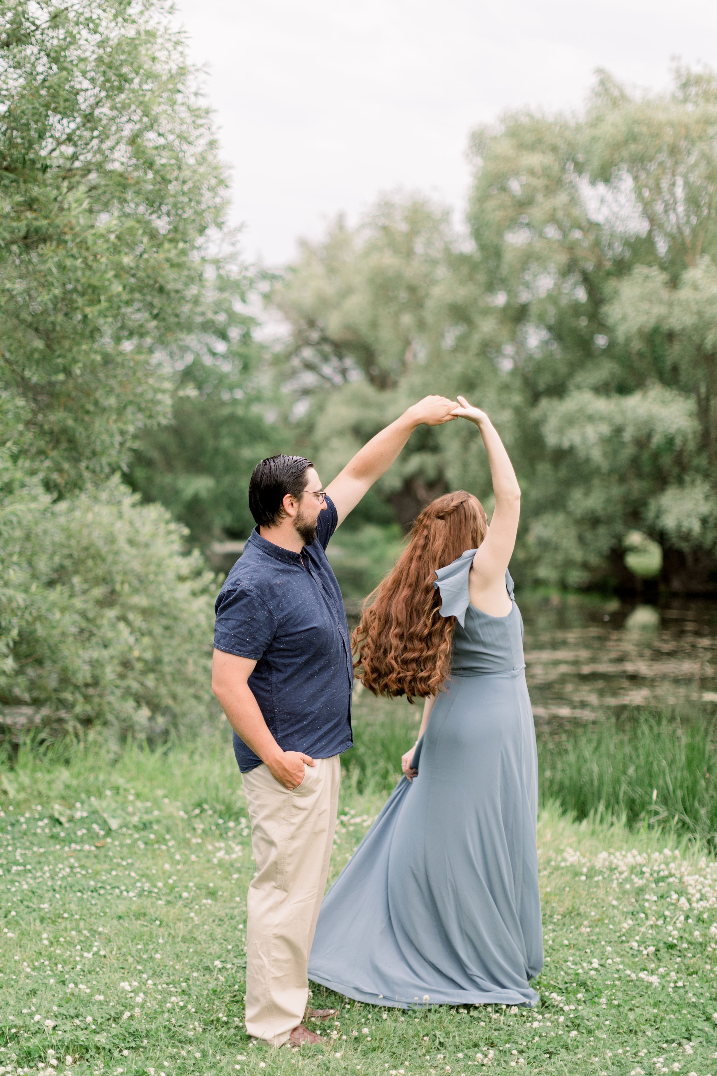  Chelsea Mason Photography captures an engaged couple dancing in a grass field at Dominion Arboretum. dancing couple in field twirling #chelseamasonphotography #chelseamasonengagements #Ottawaengagements #DominonArboretum #OttawaPhotographers&nbsp; 