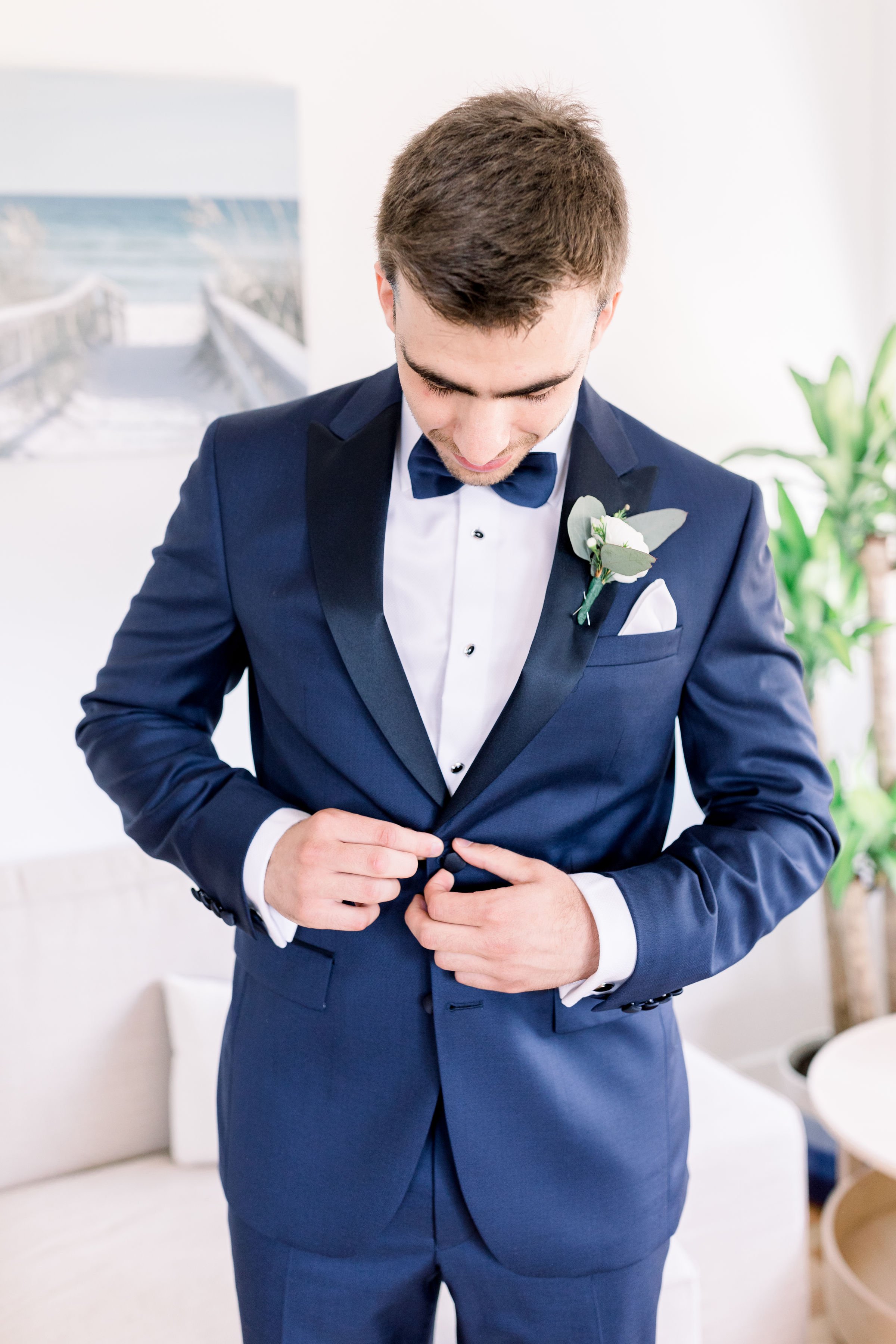  Groom in a navy suit buttons his suitcoat was captured at Evermore Weddings and Events by Chelsea Mason Photography. Navy bowtie #Chelseamasonphotography #Chelseamasonweddings #Onatarioweddings #EvermoreweddingsAlmonte #Ontarioweddingphotographers 