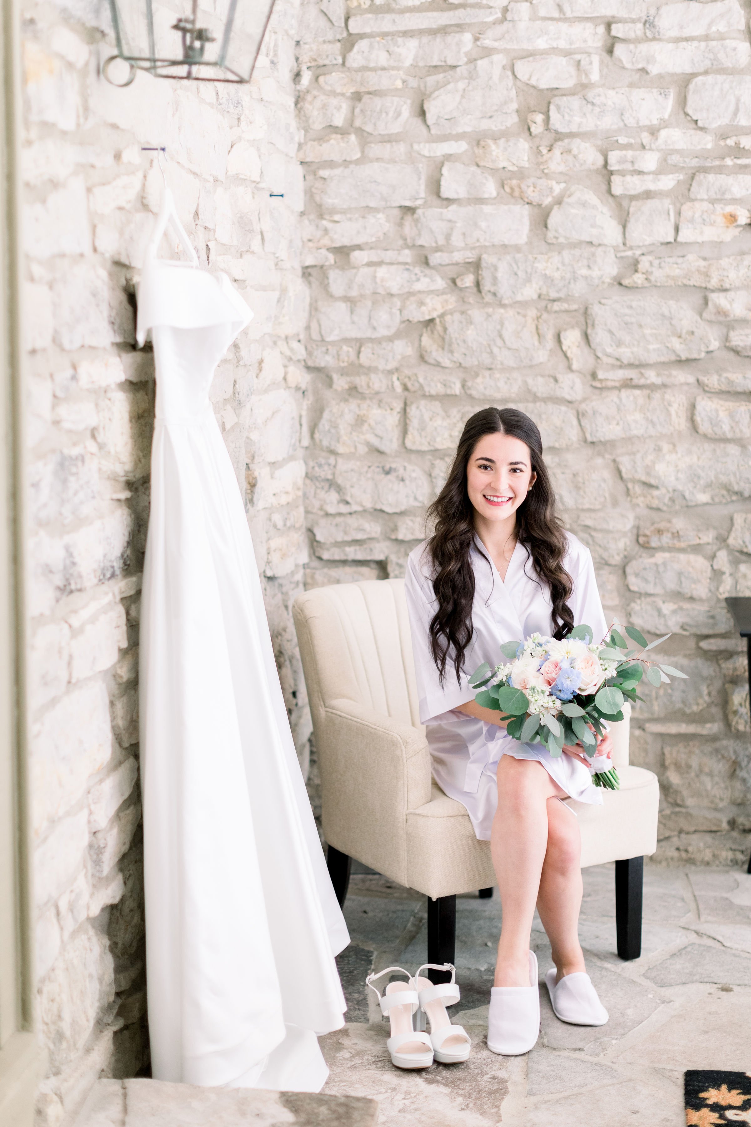  A bride in a stone room with her wedding dress and bouquet getting ready by Chelsea Mason Photography. bridal room wedding gown #Chelseamasonphotography #Chelseamasonweddings #Onatarioweddings #EvermoreweddingsAlmonte #Ontarioweddingphotographers 