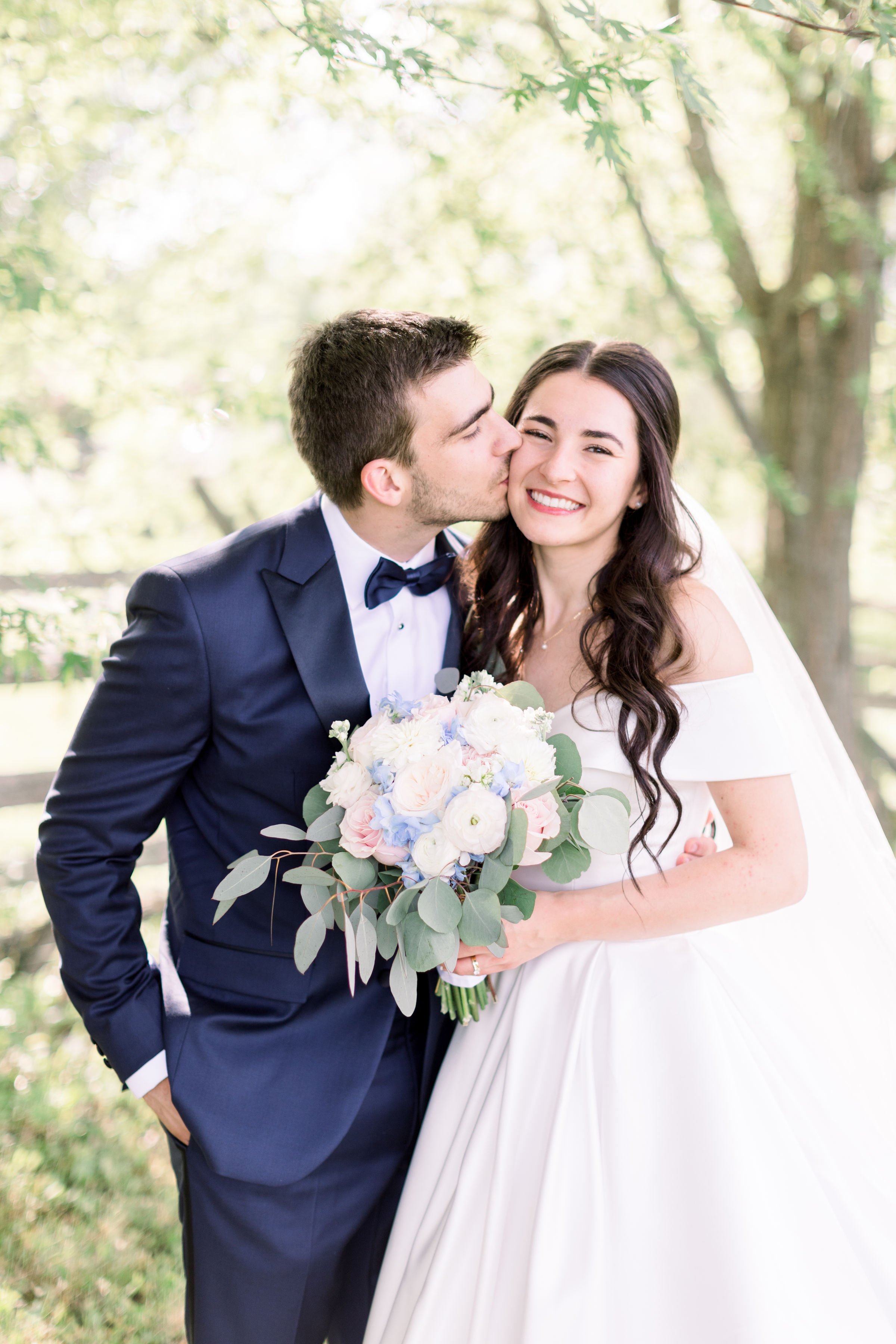  A groom in a blue suit kisses his bride's cheek captured by wedding photographer Chelsea Mason Photography. groom kisses bride #Chelseamasonphotography #Chelseamasonweddings #Onatarioweddings #EvermoreweddingsAlmonte #Ontarioweddingphotographers 