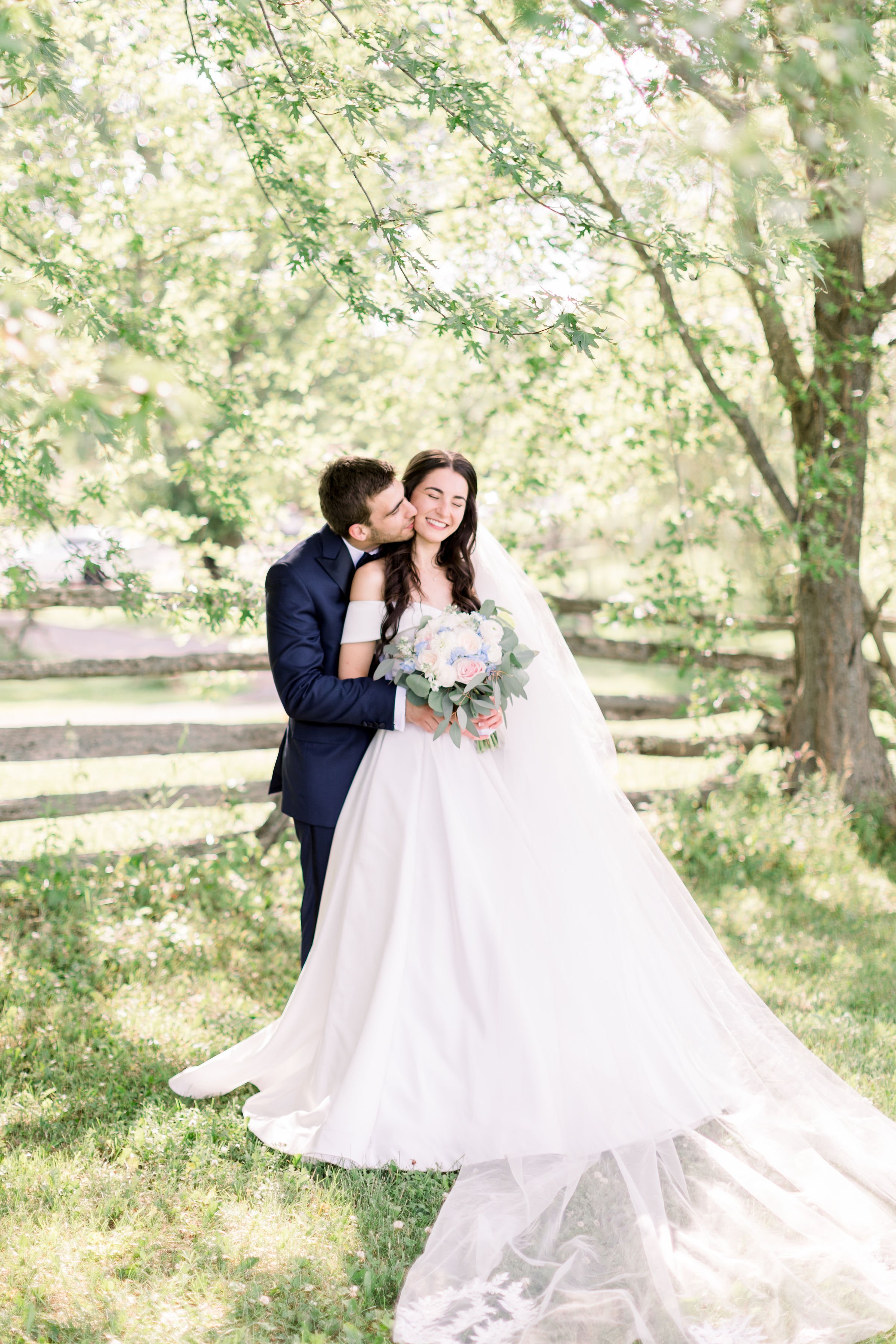  On a summer day in Almonte, Chelsea Mason Photography captures a bride smiling as the groom kisses her cheek. summer wedding inspo #Chelseamasonphotography #Chelseamasonweddings #Onatarioweddings #EvermoreweddingsAlmonte #Ontarioweddingphotographers