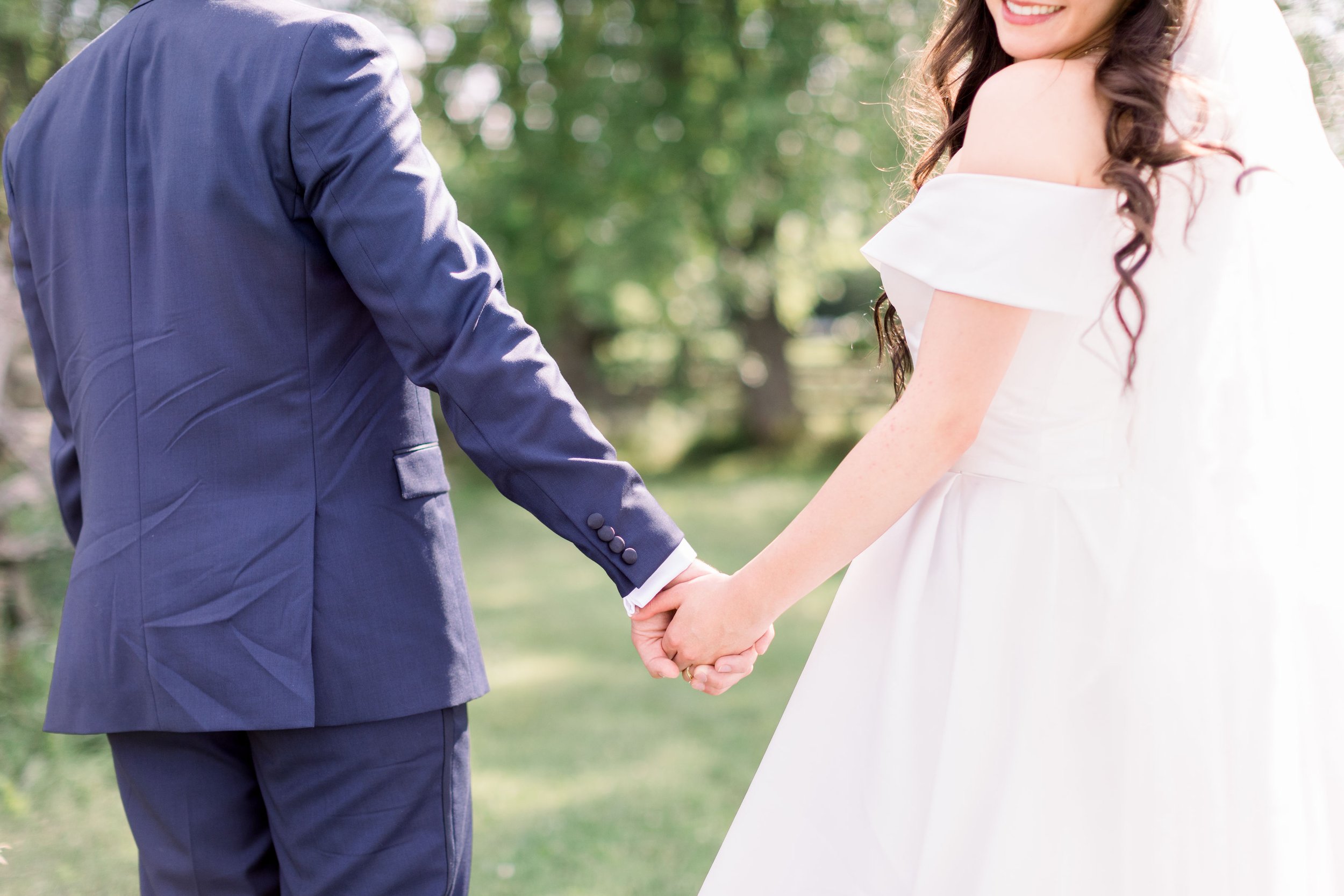  Detailed wedding portrait of bride and groom holding hands in a green field by Chelsea Mason Photography. holding hands details #Chelseamasonphotography #Chelseamasonweddings #Onatarioweddings #EvermoreweddingsAlmonte #Ontarioweddingphotographers 