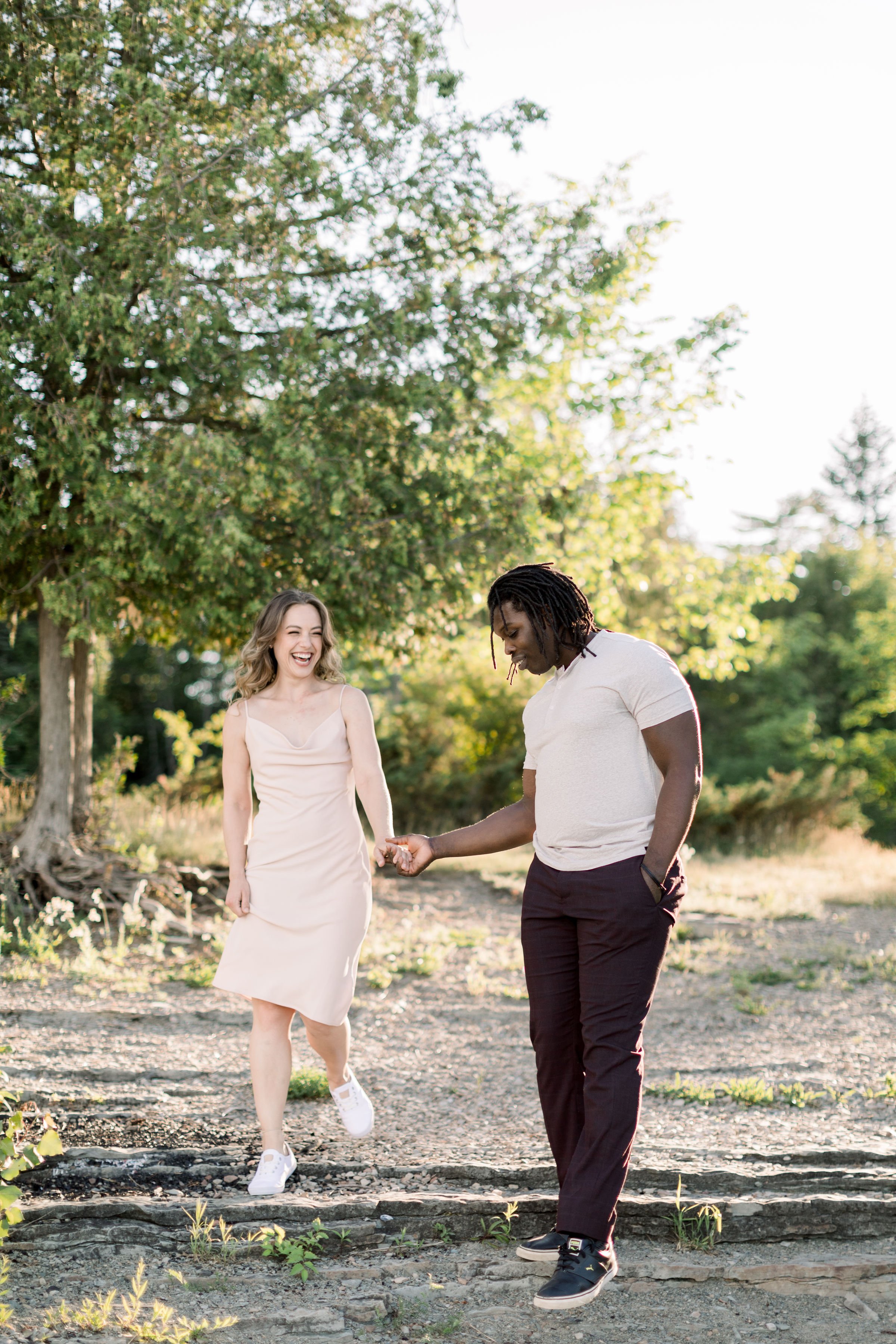 A boyfriend in a white t-shirt helps his girlfriend down some stairs by Chelsea Mason Photography. casual engagement style ideas #Chelseamasonphotography #Chelseamasonengagements #Onatarioengagements #Pinhey'sPoint #Ontarioweddingphotographers 