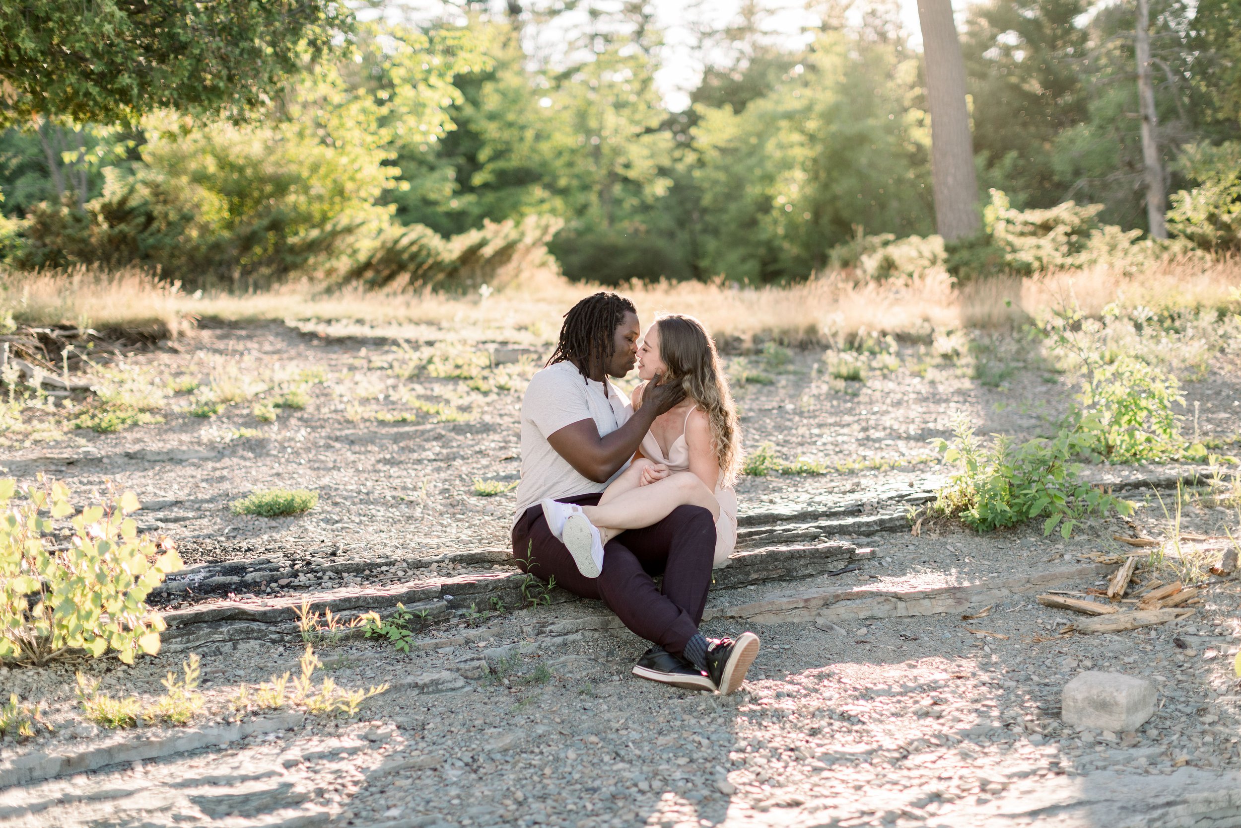  In a forest in Ontario, an engaged couple kisses on a stone stair by Chelsea Mason Photography. fiance kissing couple #Chelseamasonphotography #Chelseamasonengagements #Onatarioengagements #Pinhey'sPoint #Ontarioweddingphotographers 