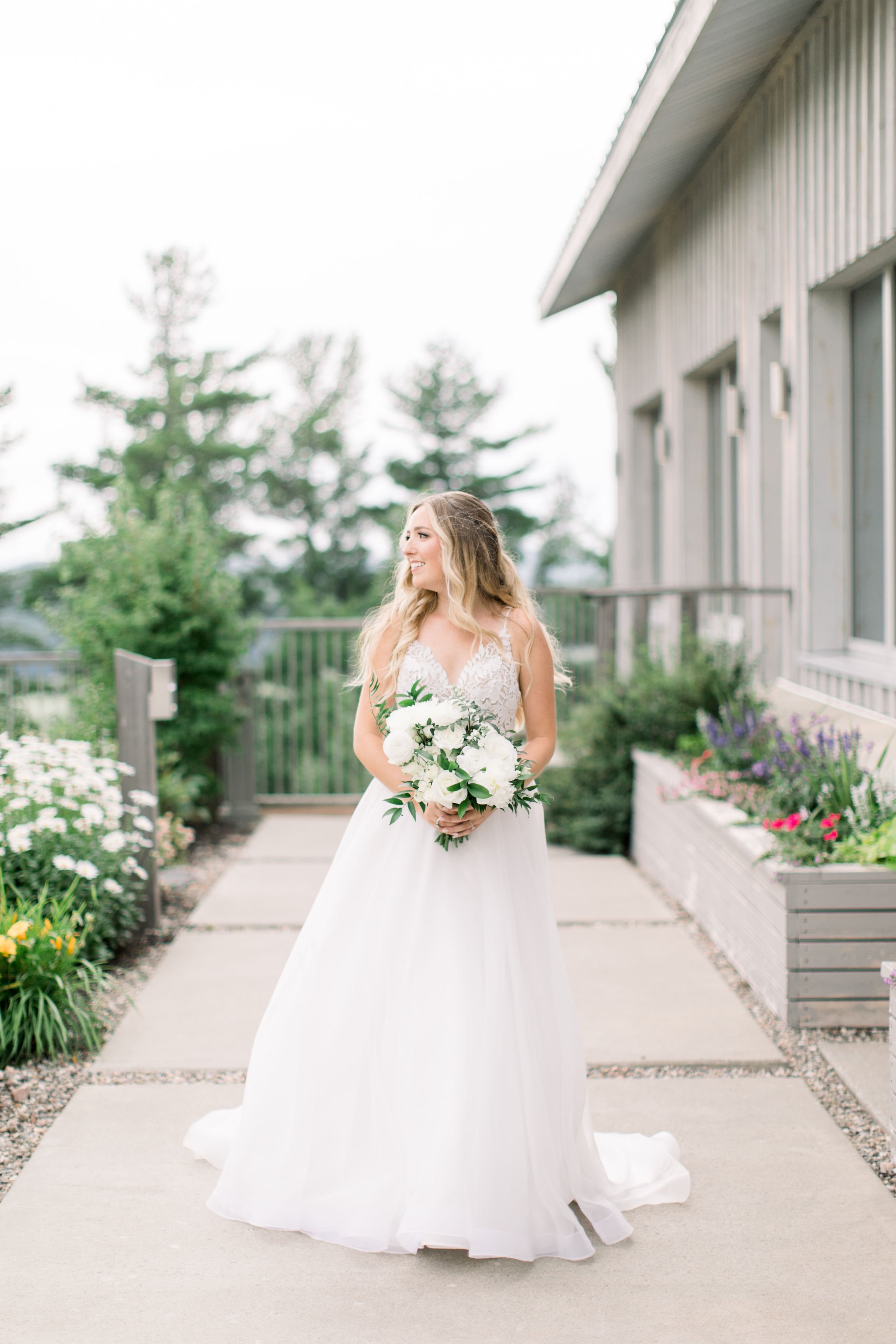  A bride in a strappy wedding dress with a white floral bouquet by Chelsea Mason Photography in Quebec. bridal portrait summer bridals #Quebecweddings #elegantoutdoorwedding #Quebecweddingphotographers #Chelseamasonphotography #Chelseamasonweddings 