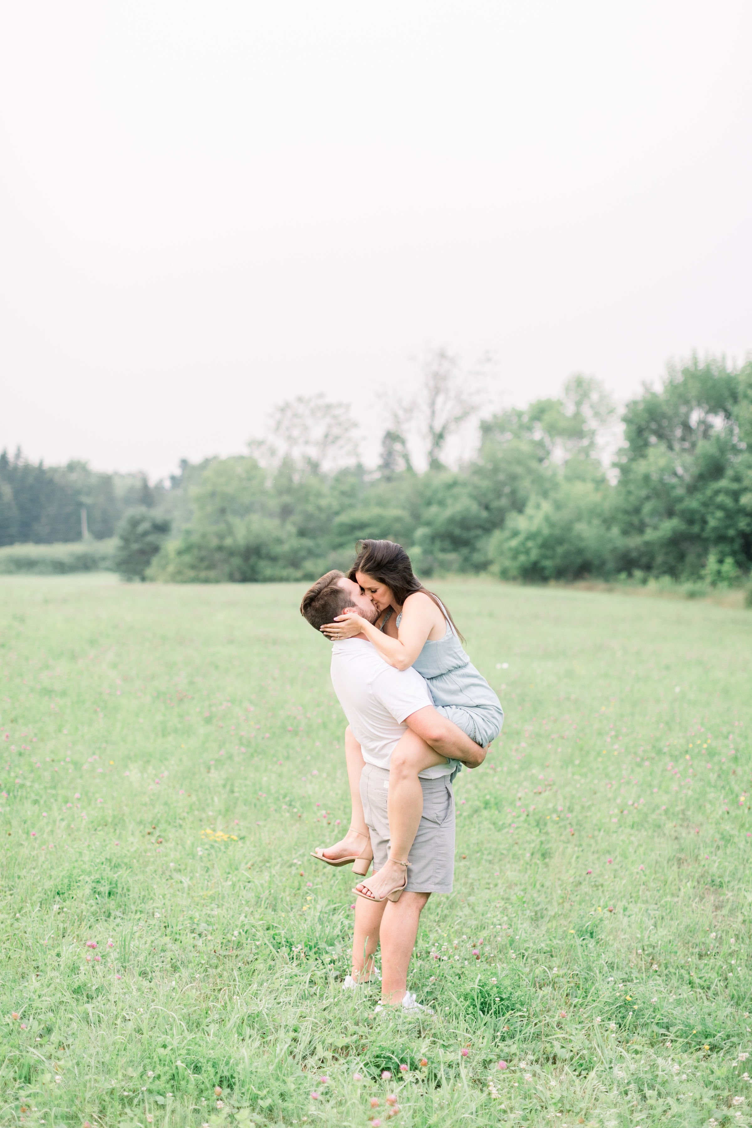  A newly engaged couple kiss passionately in a wild grass field in Kingston by Chelsea Mason Photography. holding her #Kingstonengagementlocation #GrassCreekParkPortraits #Ontarioengagementphotographer #Chelseamasonphotography #Chelseamasonengagement