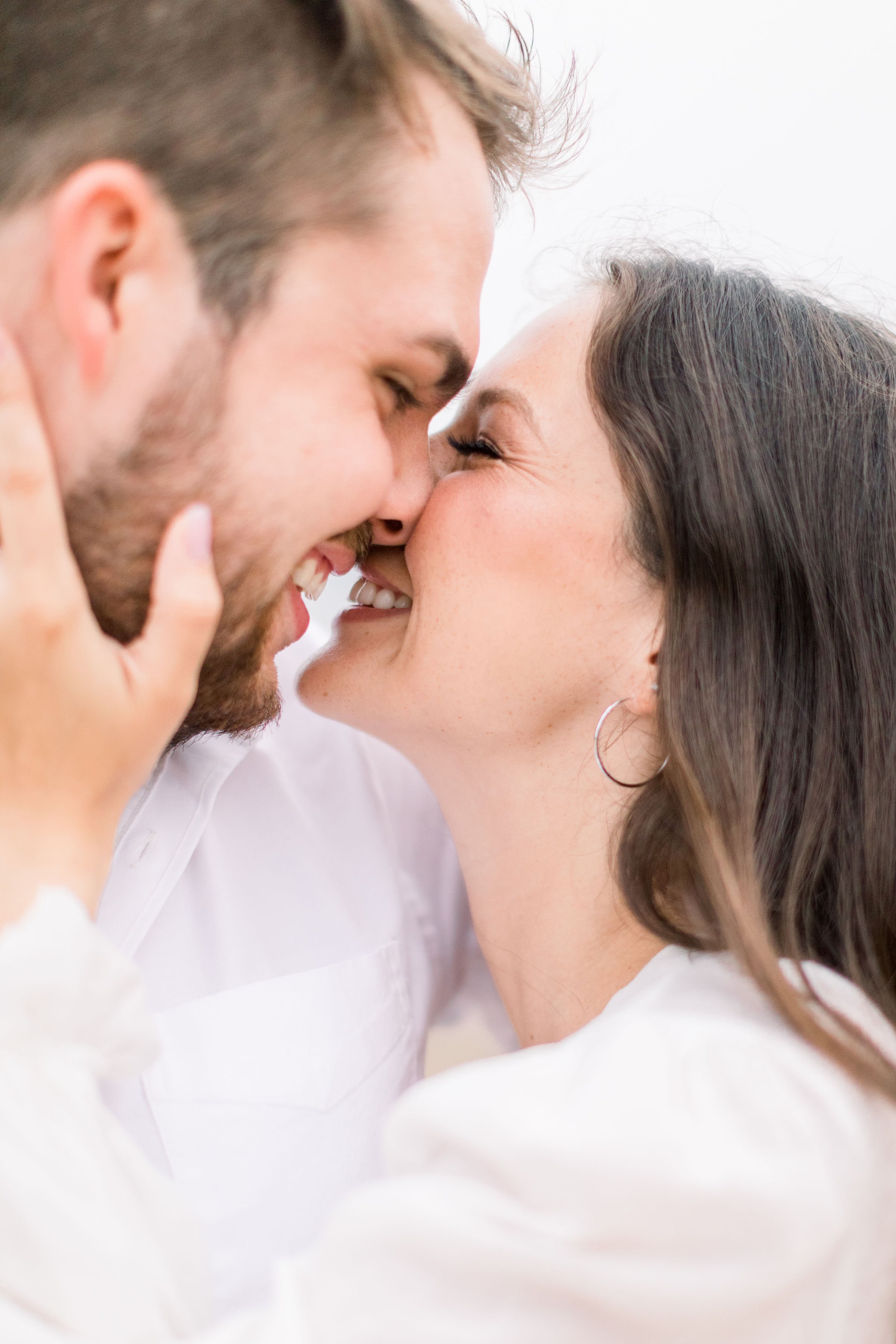  In Ontario, an engaged couple smiles while kissing one another by Chelsea Mason Photography. kissing laughing bright airy #Kingstonengagement #GrassCreekParkPortraits #Ontarioengagementphotographers #Chelseamasonphotography #Chelseamasonengagements 