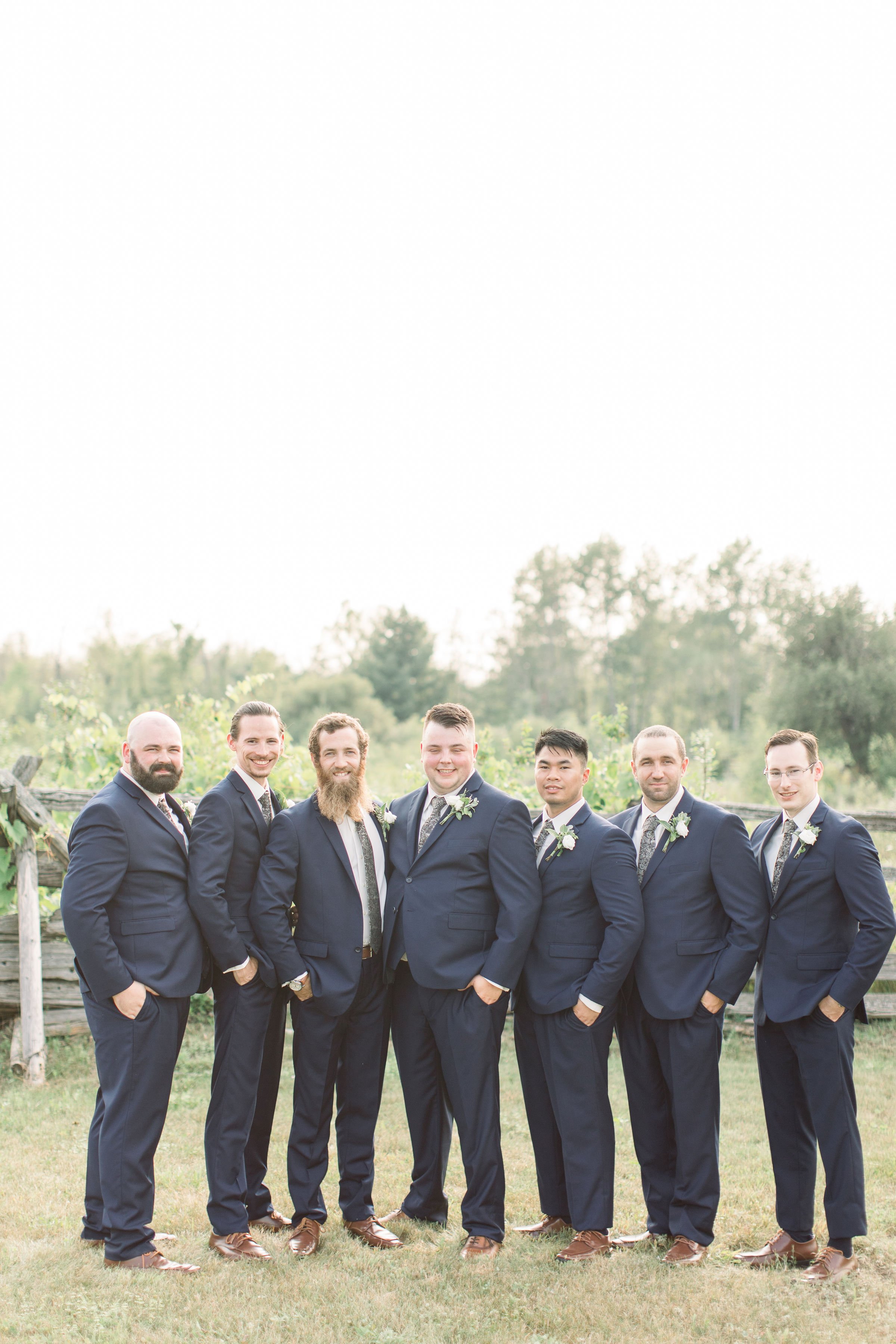  Groom with his groomsmen all wearing black in a grass field at Stonefield Estates by Chelsea Mason Photography. black suits groomsmen #StonefieldEstates #Ontarioweddings #Chelseamasonphotography #Chelseamasonengagements #Ontarioweddingphotographers 