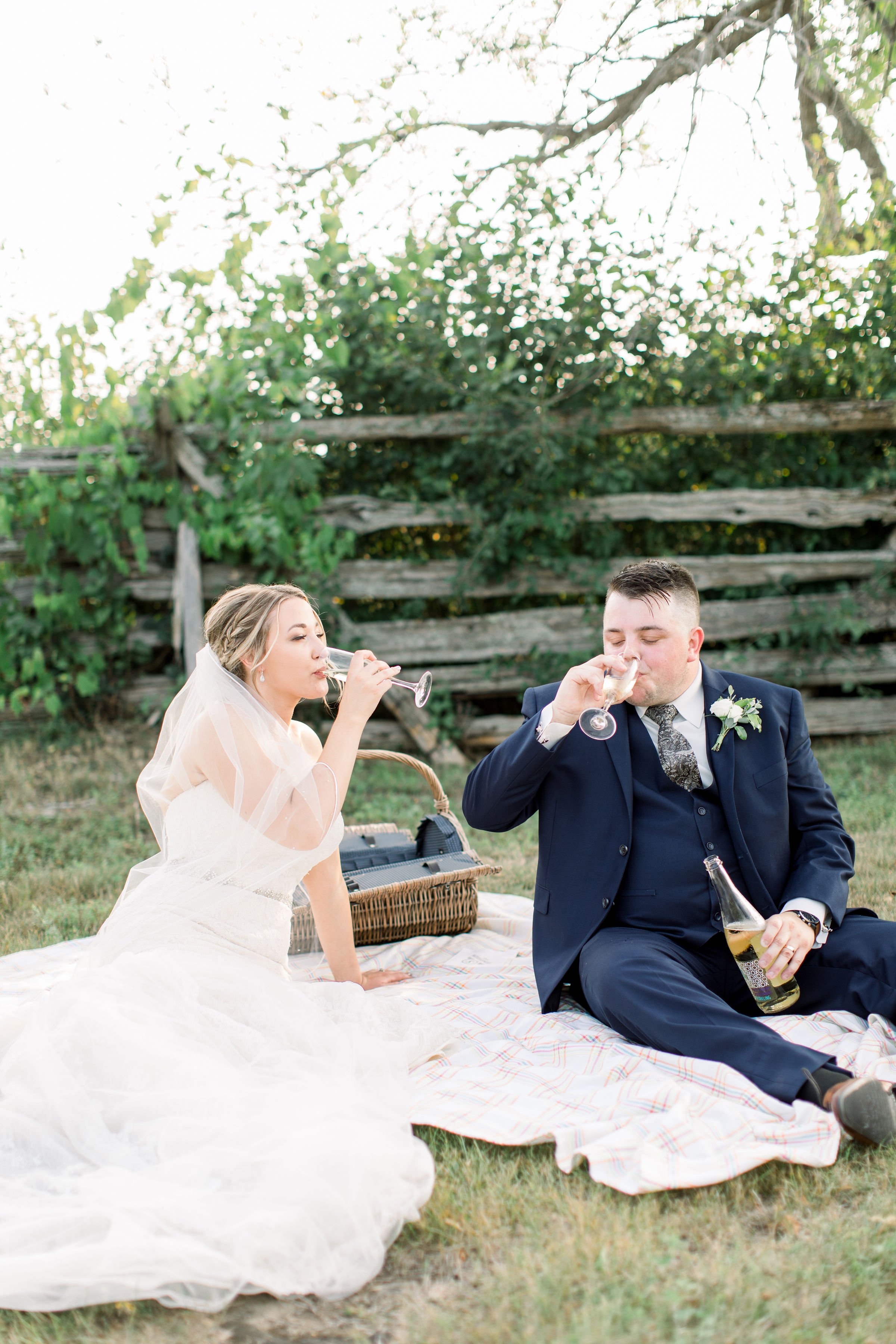  The bride and groom sit on a picnic blanket and toast on their wedding day by Chelsea Mason Photography. picnic wedding celebration #StonefieldEstates #Ontarioweddings #Chelseamasonphotography #Chelseamasonengagements #Ontarioweddingphotographers 