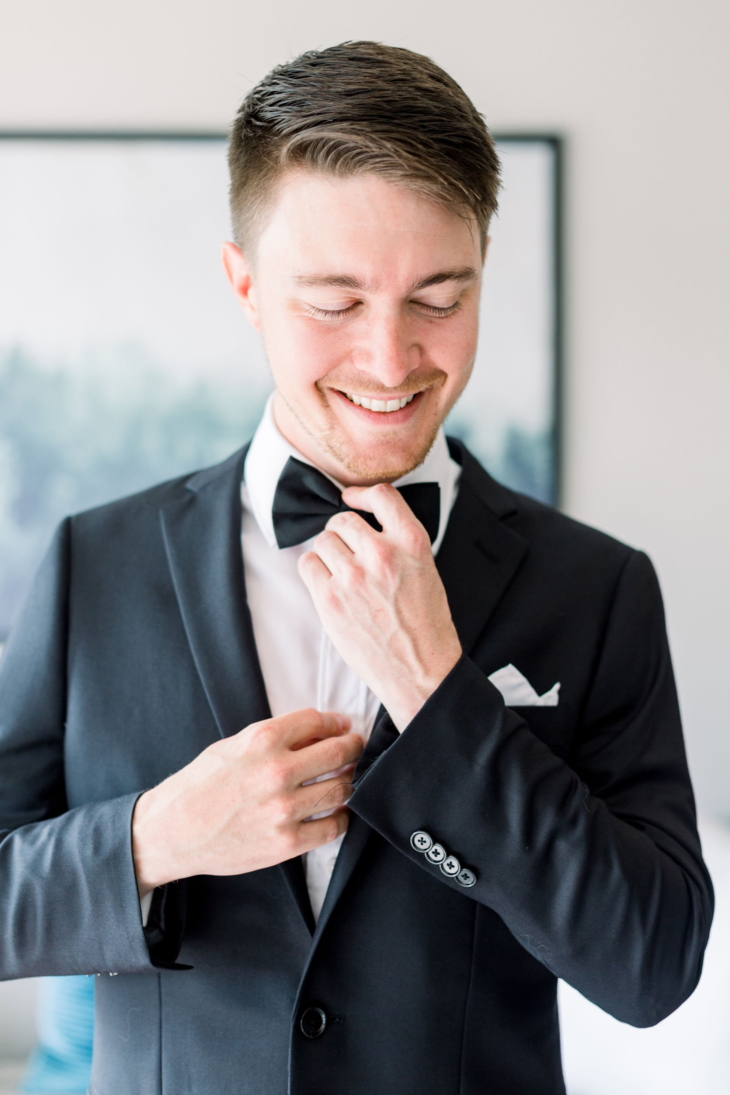  In Prince Edwards County a groom adjusts his bowtie for his wedding by Chelsea Mason Photography. groom bowtie wedding day vibes #ChelseaMasonPhotography #ChelseaMasonWeddings #PrinceEdwardsCountyWeddings #SandbanksWeddings #ONweddingphotographer 