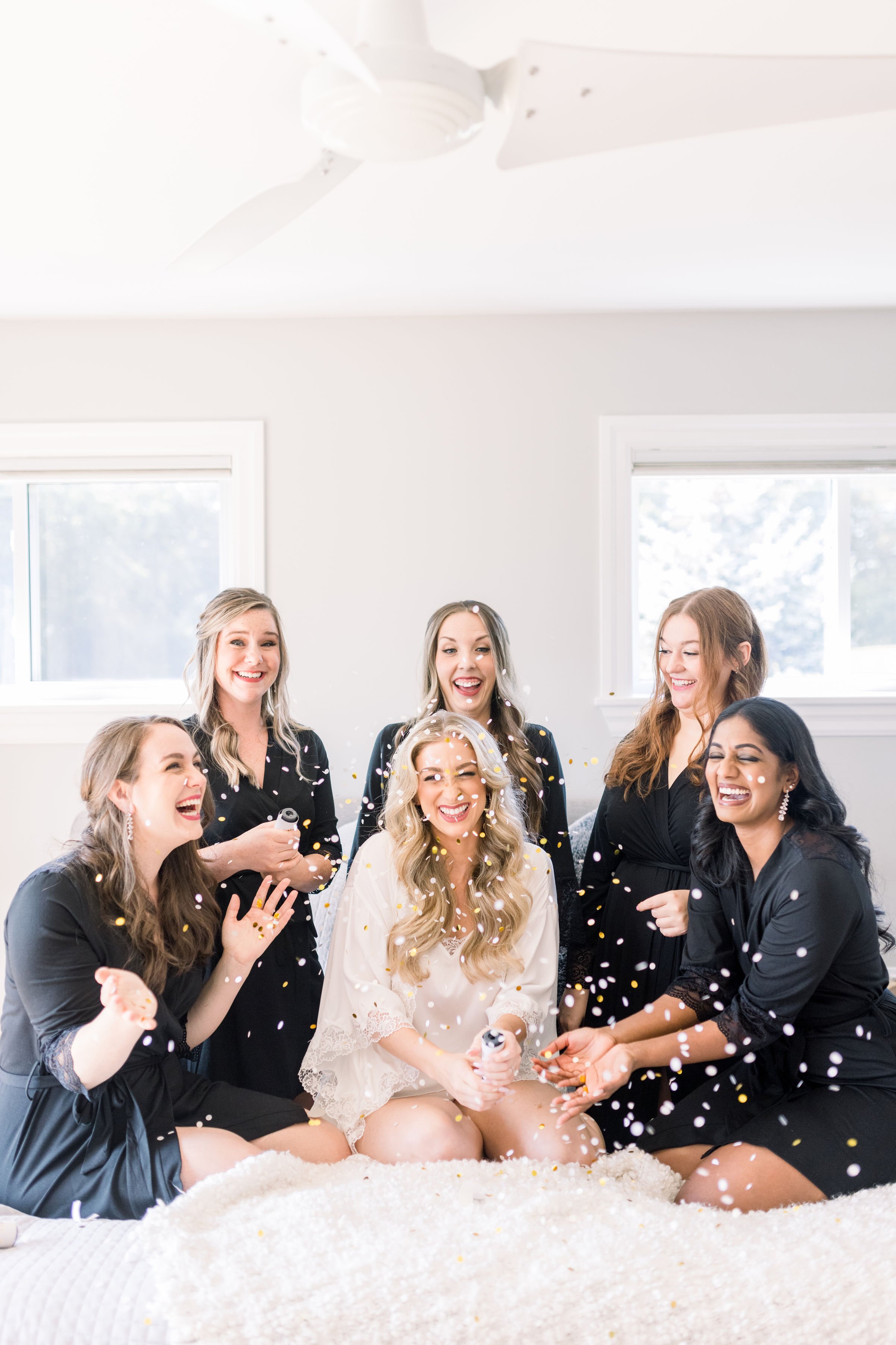  Bridesmaids throw confetti up in the air around the bride while wearing matching robes by Chelsea Mason Photography. matching robes #ChelseaMasonPhotography #ChelseaMasonWeddings #PrinceEdwardsCountyWeddings #SandbanksWeddings #ONweddingphotographer