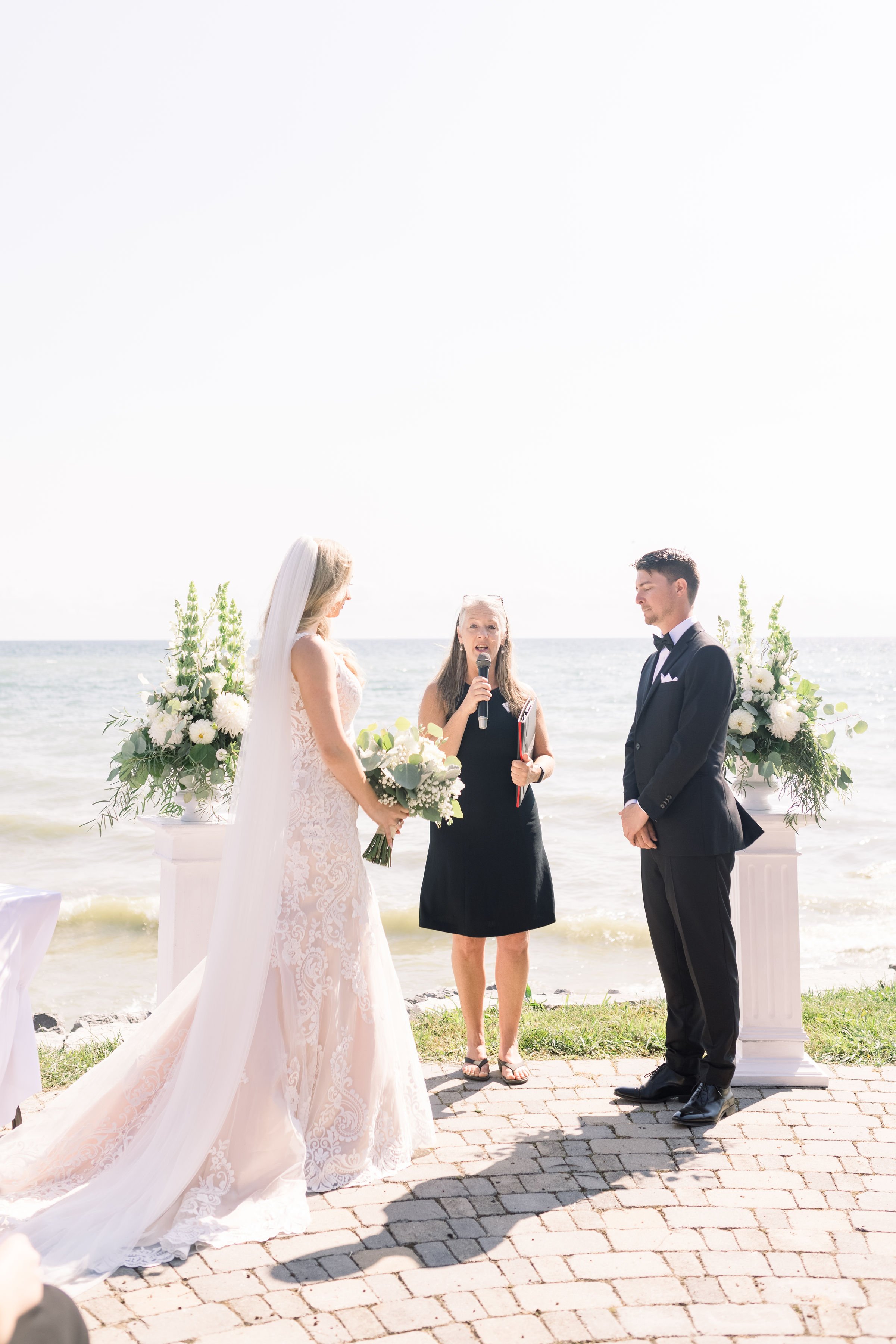  A bride and groom stand at the altar on the beachfront captured by Chelsea Mason Photography. lake wedding getting married #ChelseaMasonPhotography #ChelseaMasonWeddings #PrinceEdwardsCountyWeddings #SandbanksWeddings #ONweddingphotographer 