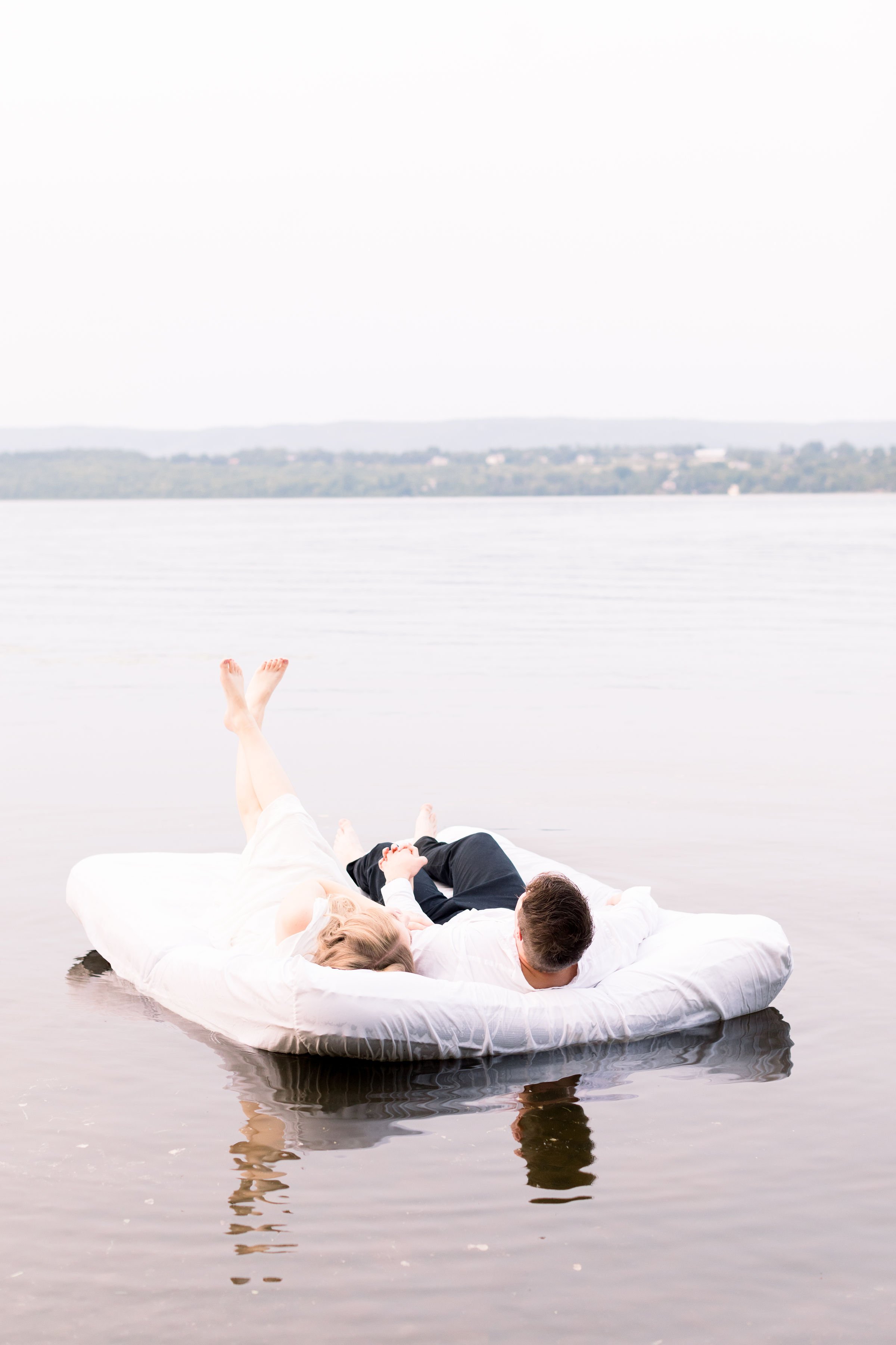  In Ottawa, a couple takes portraits while laying on a mattress on a lake by Chelsea Mason Photography. mattress on a lake unique engagements #ChelseaMasonPhotography #ChelseaMasonEngagements #PinheysPointEngagements #OttawaEngagementPhotography 
