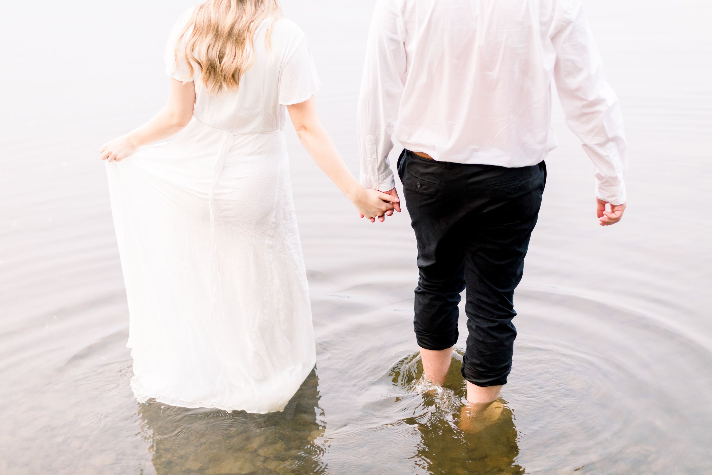  Chelsea Mason Photography captures a man and woman holding hands while walking into a lake. Pinhey's Point Engagements Ottawa Photographers #ChelseaMasonPhotography #ChelseaMasonEngagements #PinheysPointEngagements #OttawaEngagementPhotography 