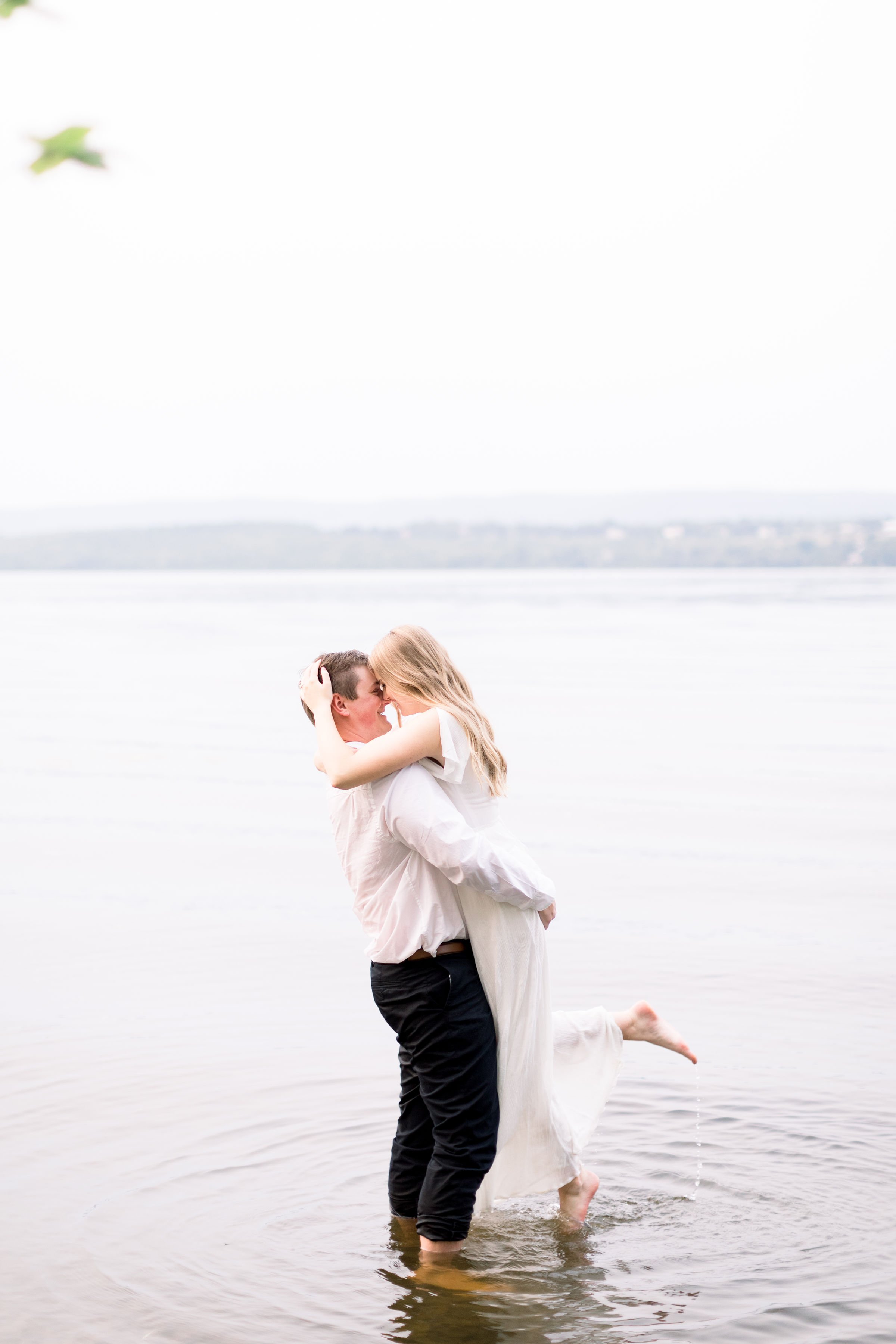  Man and woman hold each other tightly while standing in a lake by Chelsea Mason Photography. Ottawa professional photographers bare feet #ChelseaMasonPhotography #ChelseaMasonEngagements #PinheysPointEngagements #OttawaEngagementPhotography 