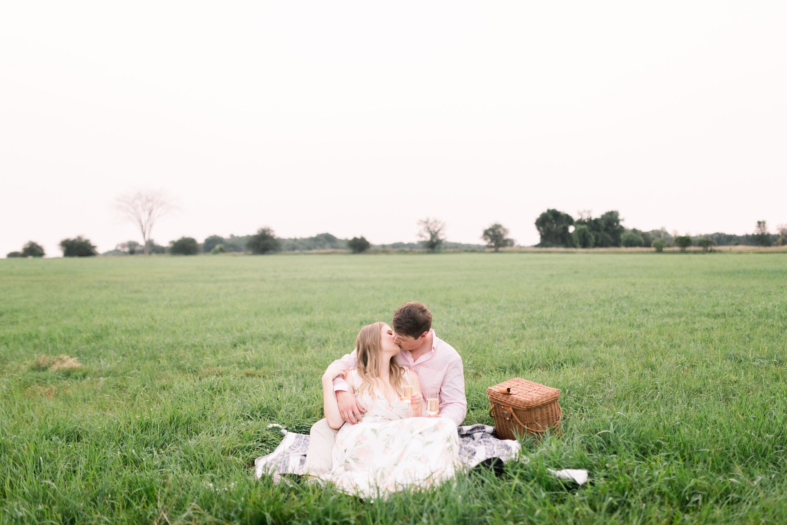  Chelsea Mason Photography captures soon-to-be newlyweds kissing on a picnic blanket in the springtime. Spring picnic engagement photography #ChelseaMasonPhotography #ChelseaMasonEngagements #PinheysPointEngagements #OttawaEngagementPhotography 