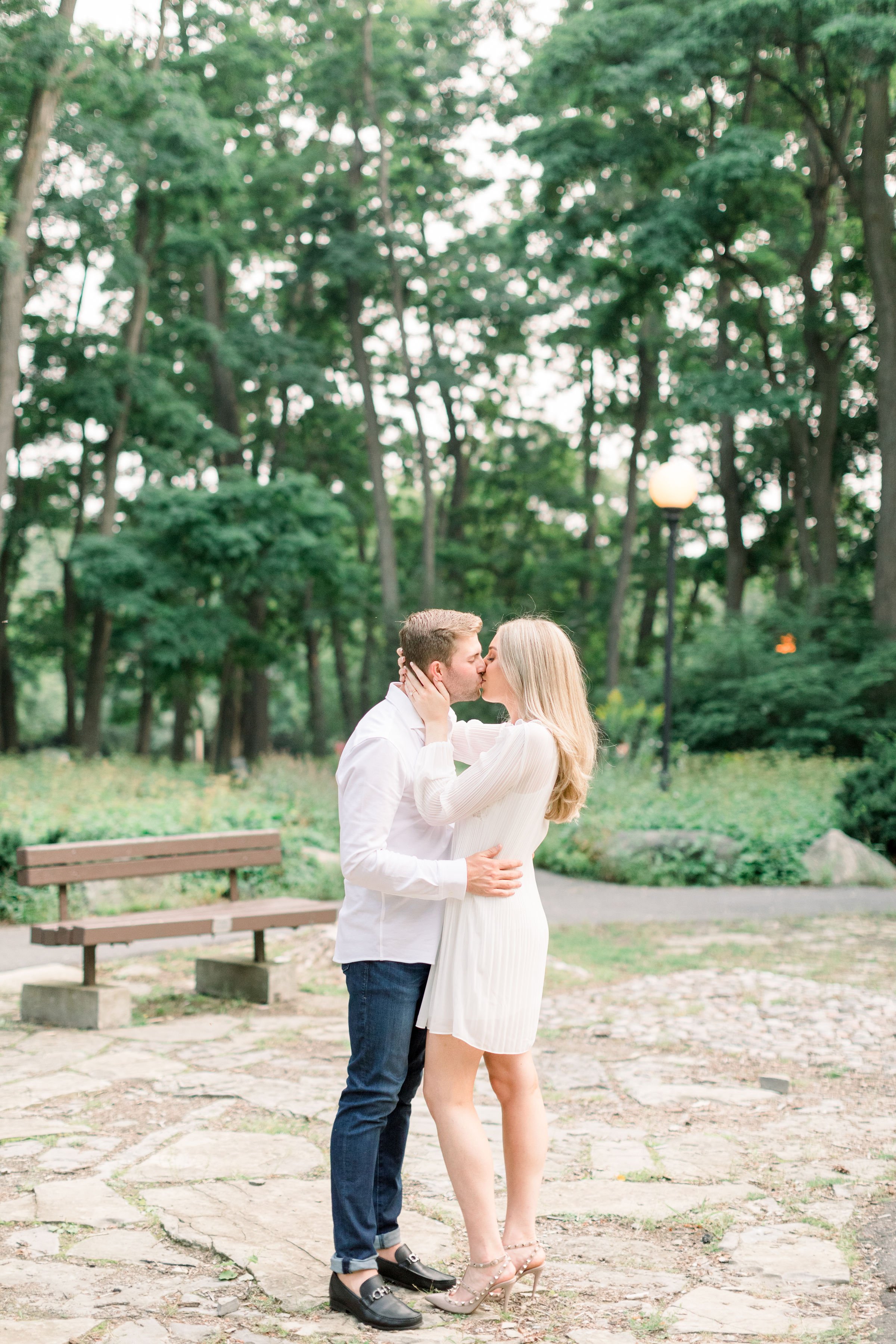  A couple kisses while standing on a stone pathway in an Ottawa park by Chelsea Mason Photography. kissing fiances wedding pictures #Ottawaengagements #Ottawaweddingphotographers #engagementwithdogs #ChelseaMasonPhotography #ChelseaMasonEngagements  