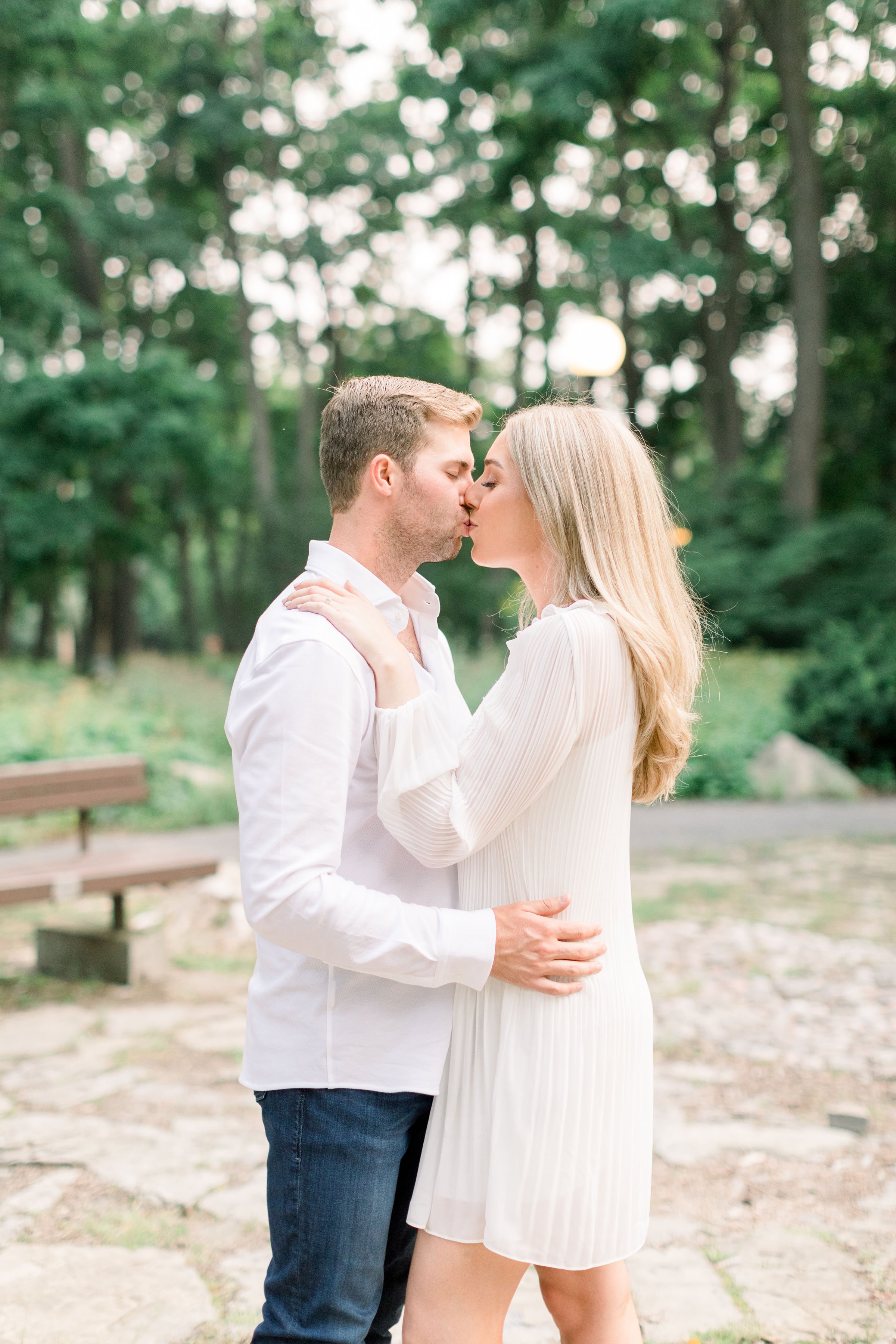  A blonde couple wearing an all-white kiss in a park plaza in Ottawa by Chelsea Mason Photography. couple goals summer wedding inspo #Ottawaengagements #Ottawaweddingphotographers #engagementwithdogs #ChelseaMasonPhotography #ChelseaMasonEngagements 