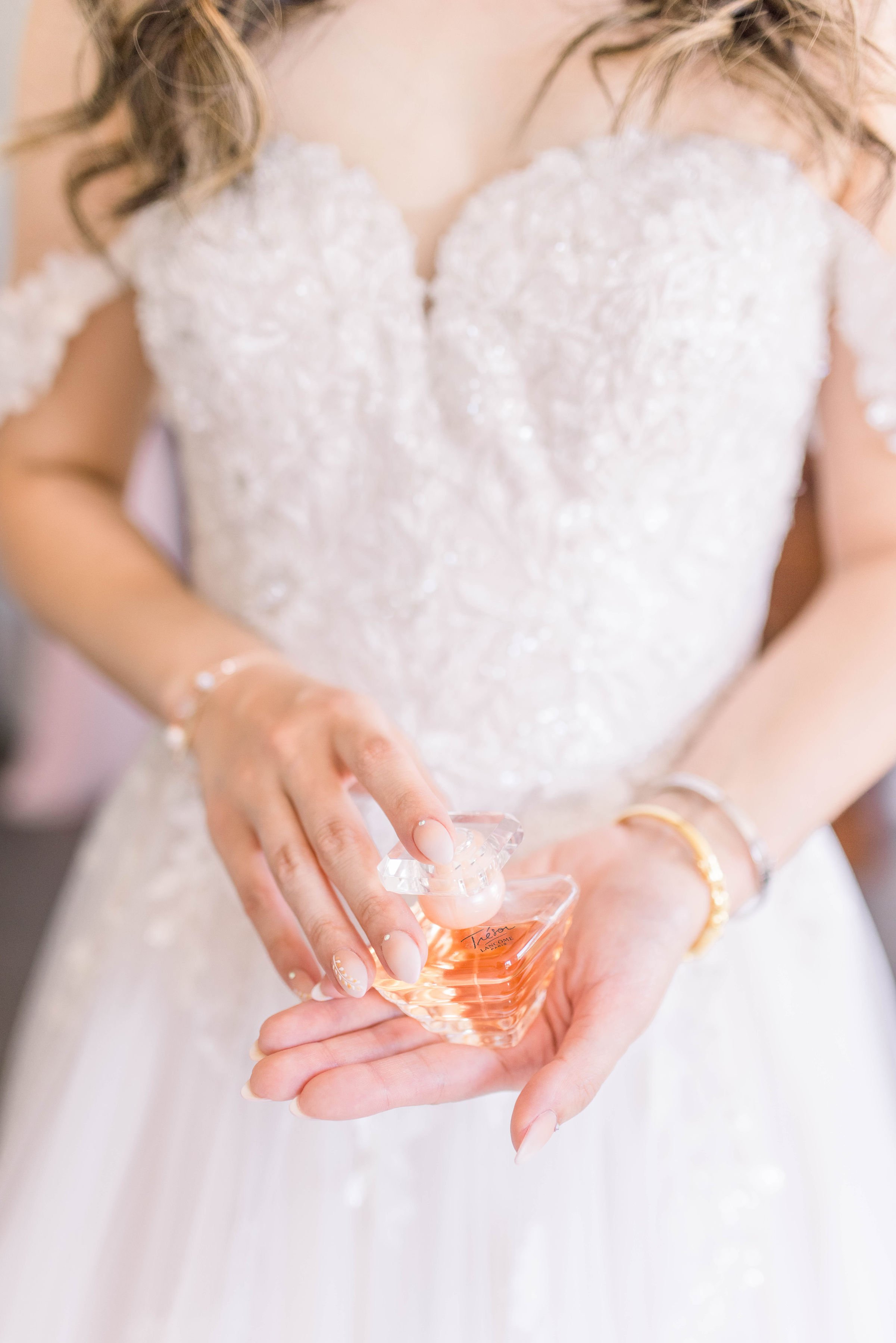  Detailed photo of a bride holding her perfume in her wedding gown by Chelsea Mason Photography. wedding gown off the shoulders #ChelseaMasonPhotography #ChelseaMasonWeddings #DowntownOttawa #FairmontChateauLaurier #OttawaWeddings #OttawaPhotographer