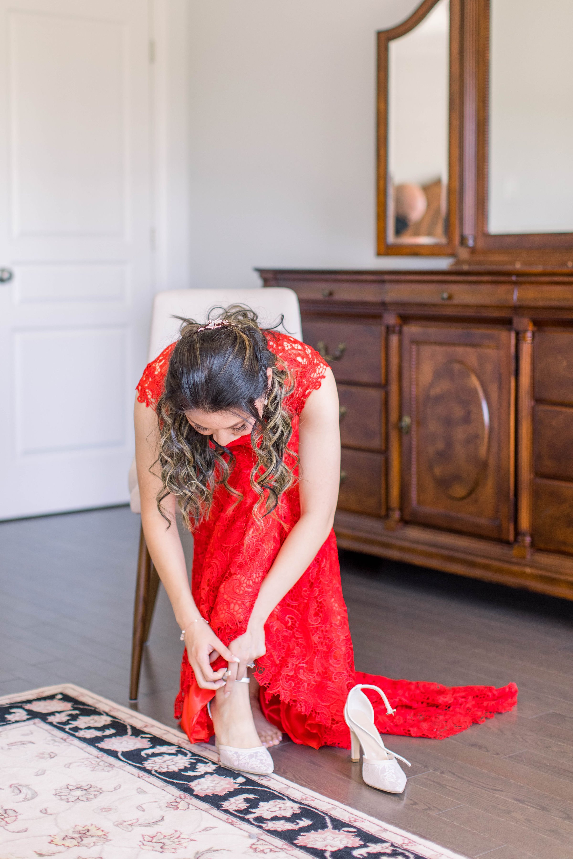  A bride wearing red lace dress putting her shoes on by Chelsea Mason Photography. shoes Fairmont Chateau Laurier weddings #ChelseaMasonPhotography #ChelseaMasonWeddings #DowntownOttawa #FairmontChateauLaurier #OttawaWeddings #OttawaPhotographers 