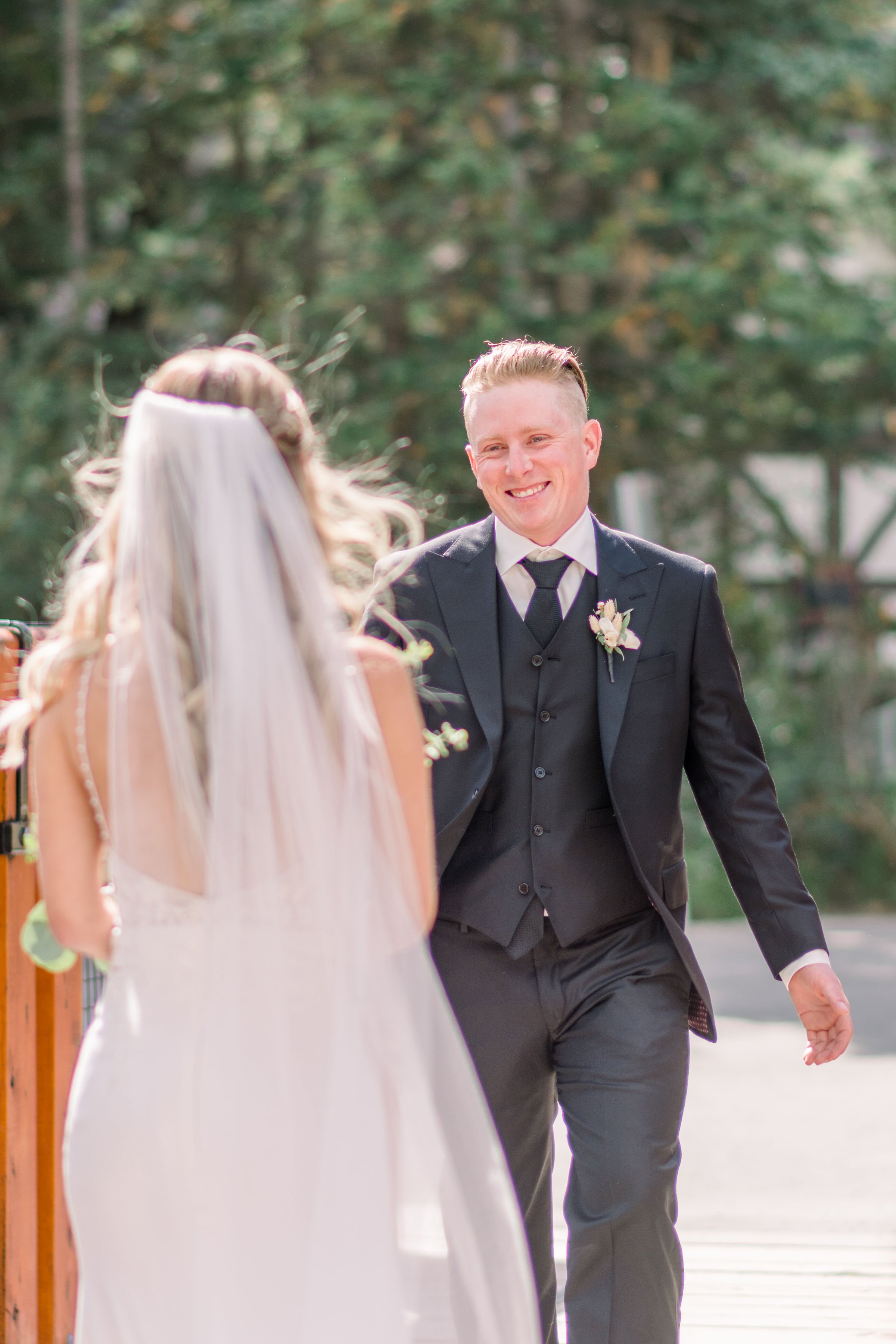  A groom gets the first look at his bride and smiles brightly by Chelsea Mason Photography. first look groom in love #Albertaweddings #shesaidyes #Albertaweddingphotographers #SilvertipGolfCourse #ChelseaMasonPhotography #ChelseaMasonWeddings  