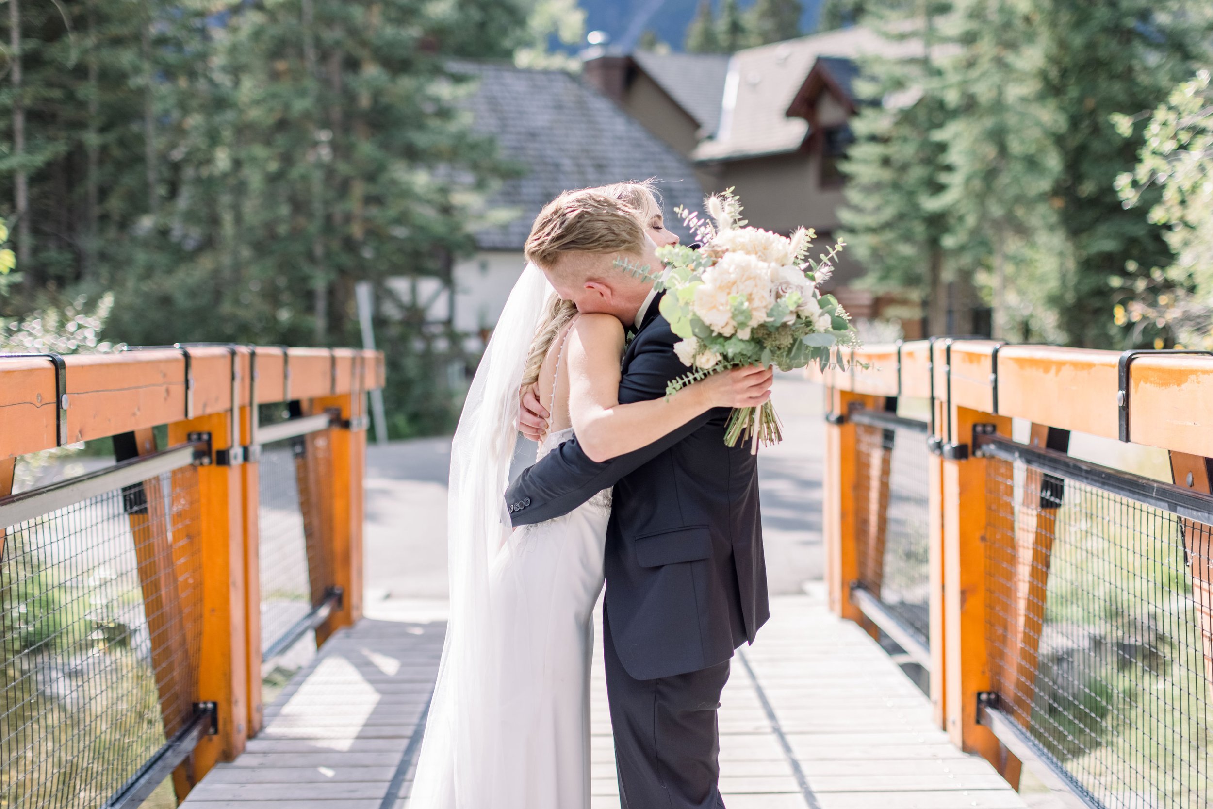  Bride and groom hug on a wooden forest bridge in the Alberta mountains by Chelsea Mason Photography. hugging bride groom #Albertaweddings #shesaidyes #Albertaweddingphotographers #SilvertipGolfCourse #ChelseaMasonPhotography #ChelseaMasonWeddings  