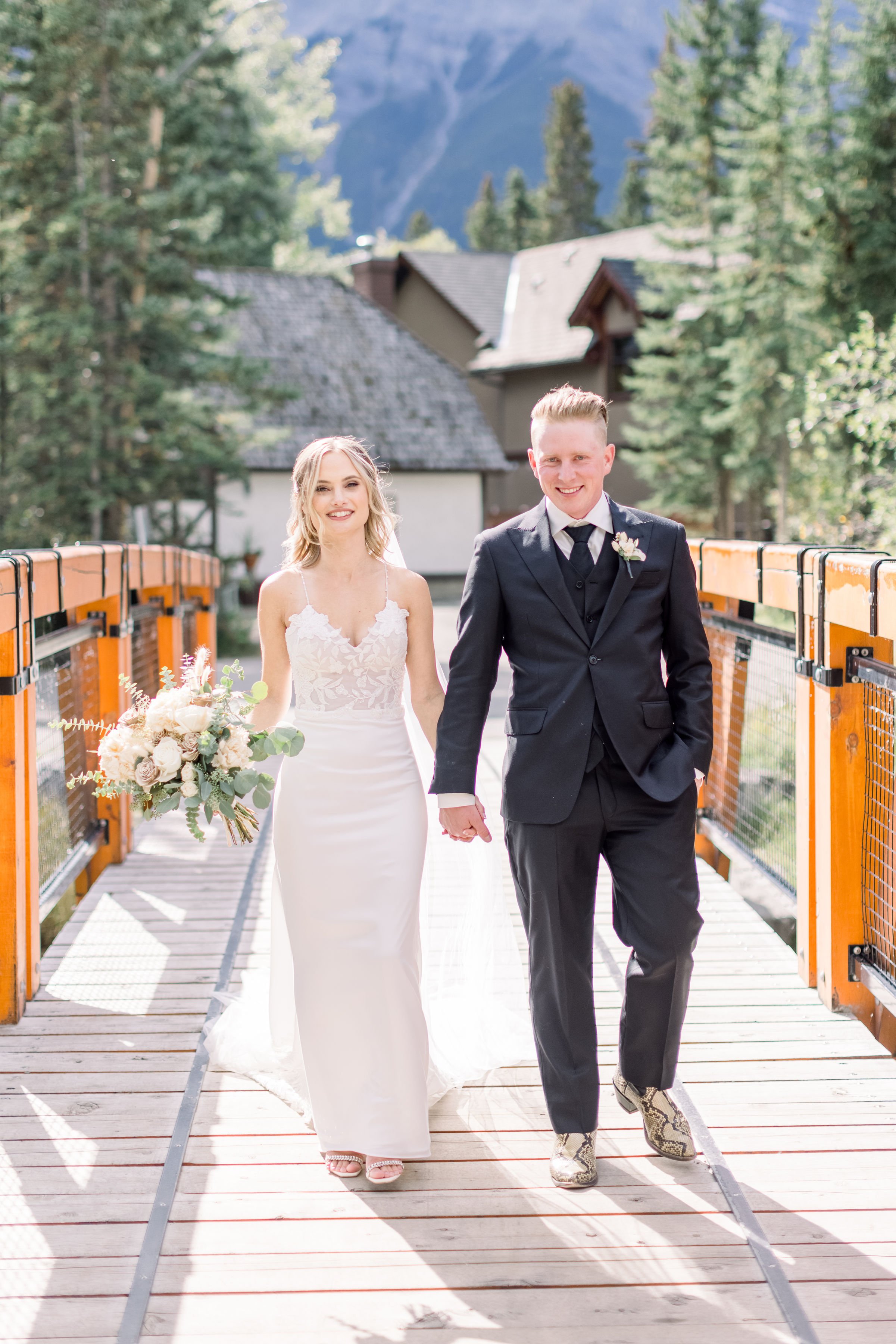  Chelsea Mason Photography captures the bride and groom walking hand in hand during a forest wedding. newlywed portraits #Albertaweddings #shesaidyes #Albertaweddingphotographers #SilvertipGolfCourse #ChelseaMasonPhotography #ChelseaMasonWeddings  