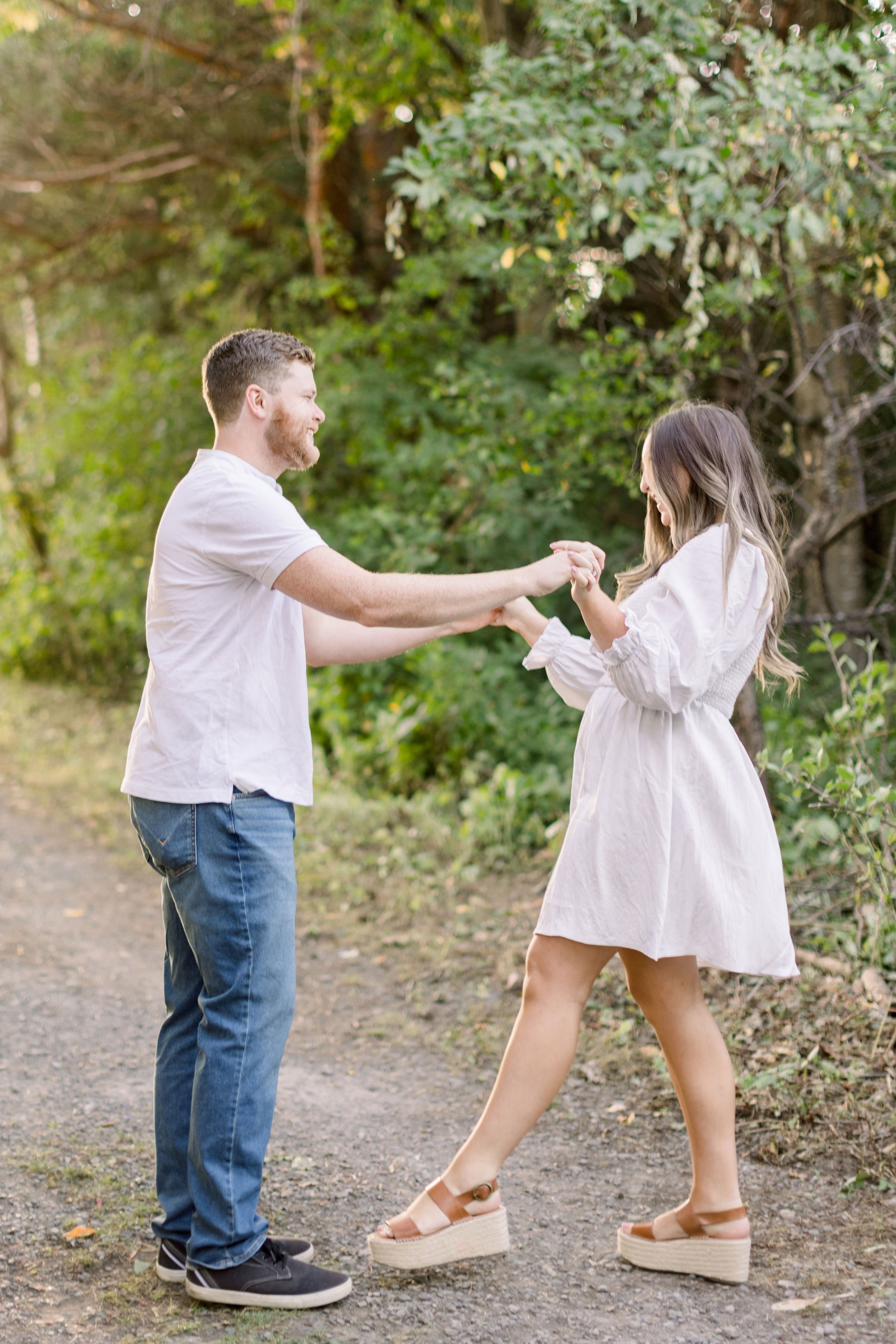  Chelsea Mason Photography captures an engaged couple dancing together under some trees in Ottawa. Ottawa engagements #ChelseaMasonPhotography #ChelseaMasonEngagements #Ottawaphotographers #ArboretumOttawaEngagments #weddingannouncementportraits 