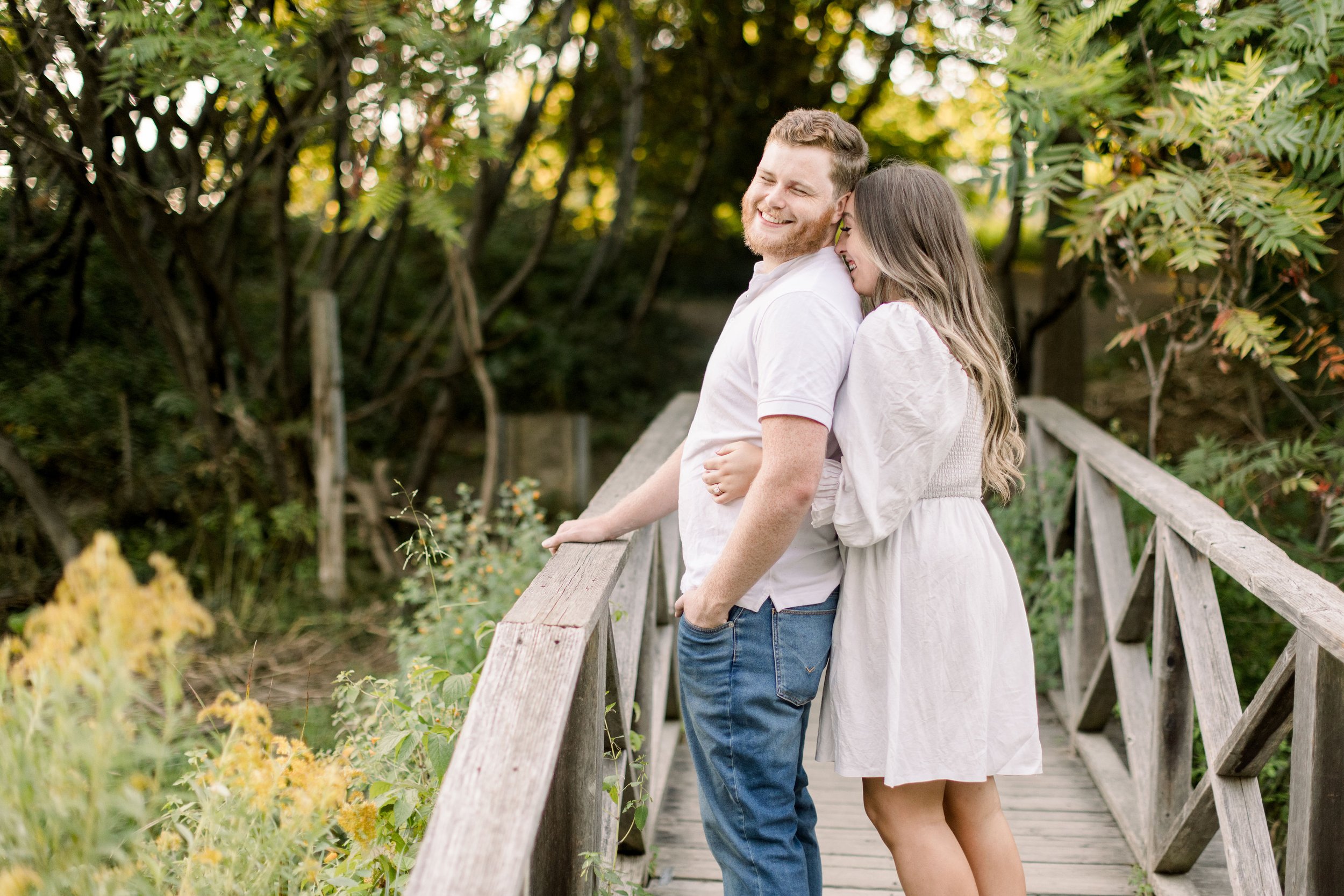  A woman hugs her boyfriend from behind and snuggles in by Chelsea Mason Photography. engagement poses #ChelseaMasonPhotography #ChelseaMasonEngagements #Ottawaphotographers #ArboretumOttawaEngagments #weddingannouncementportraits 