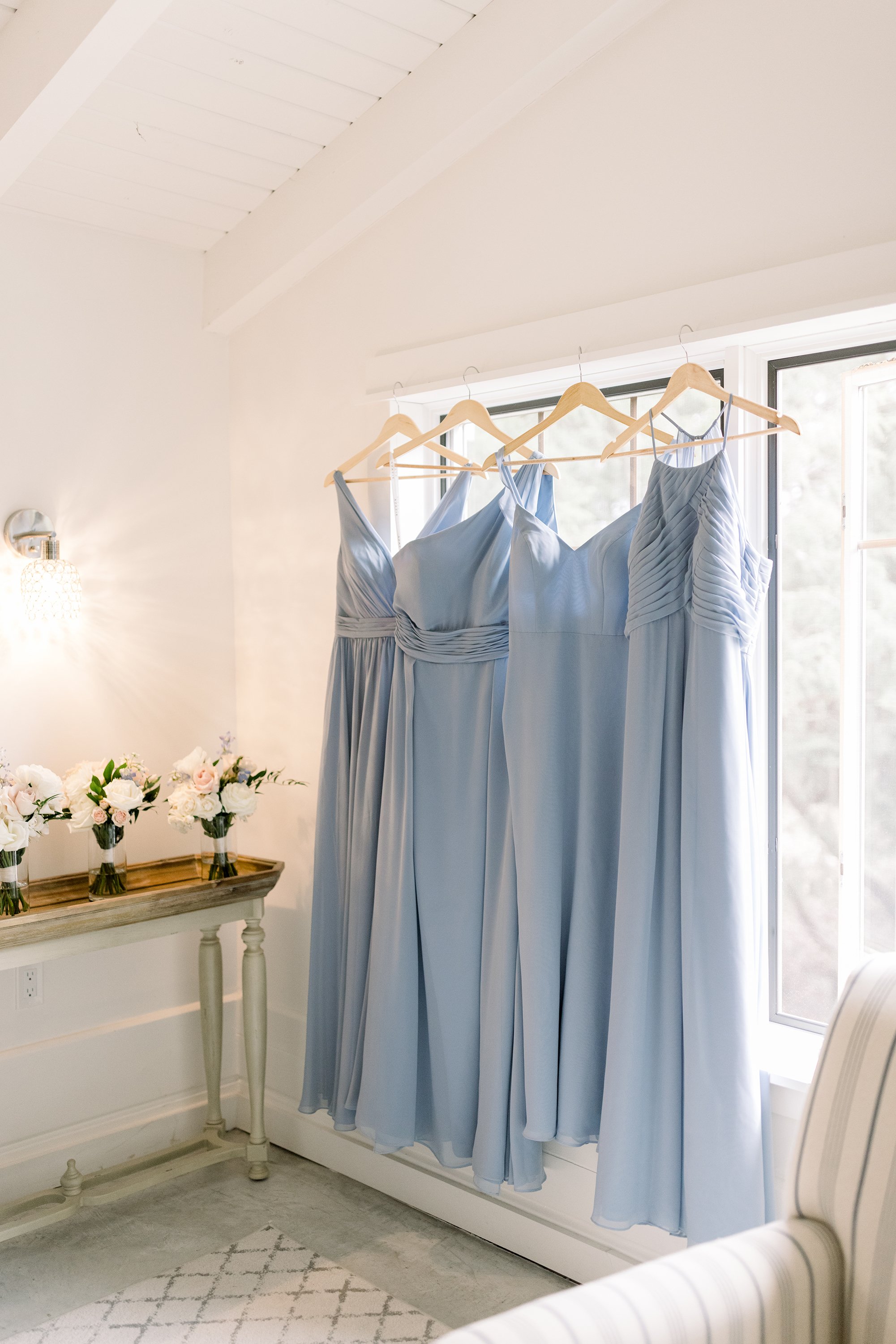  Light blue bridesmaid gowns hanging in a window in the bridal suite were captured by Chelsea Mason Photography. blue bridesmaid gowns #ChelseaMasonPhotography #ChelseaMasonWeddings #WakefieldWeddings #LeBelvedere #Wakefieldweddingphotographers 
