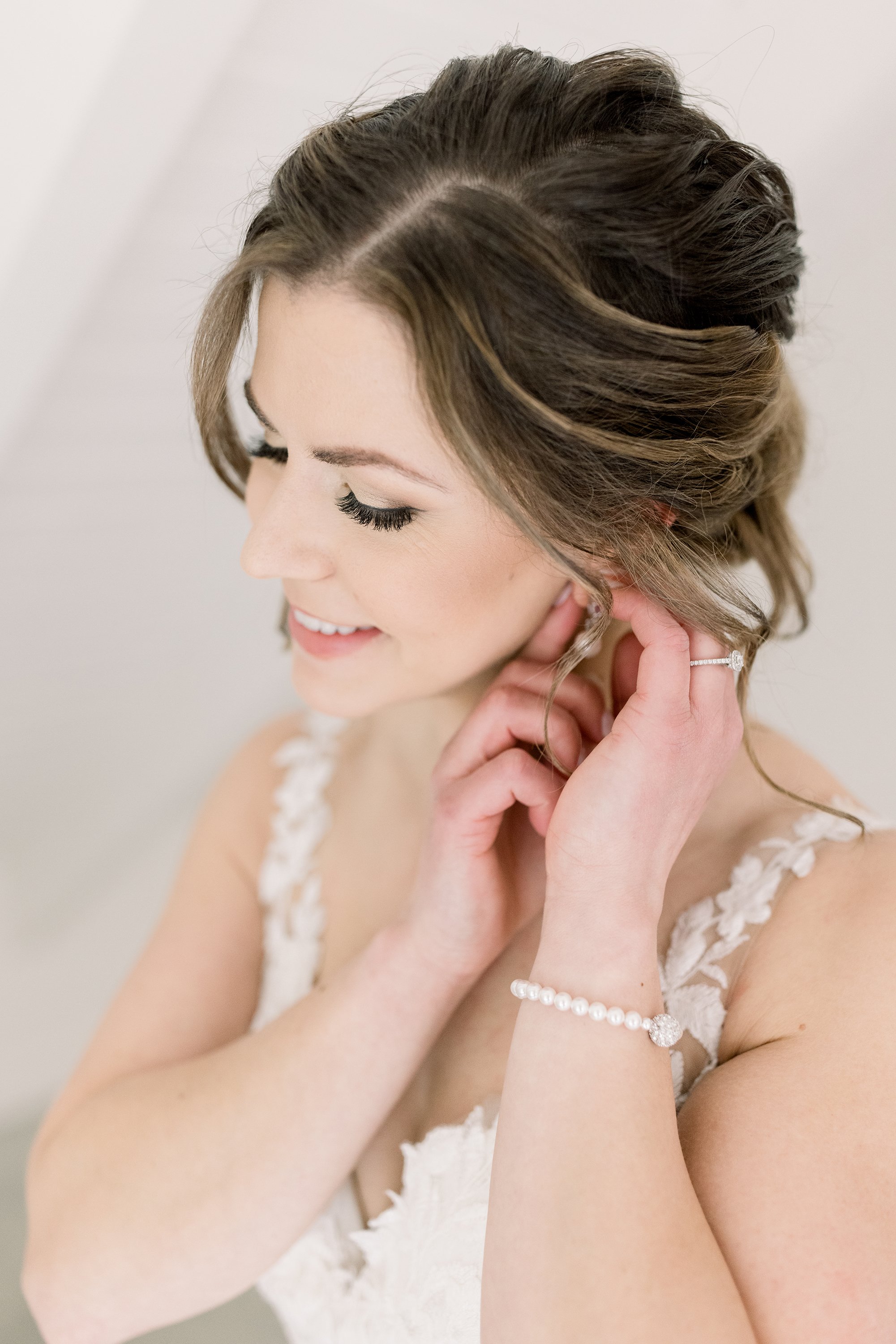  Wedding photographer Chelsea Mason Photography captures a close-up portrait of a bride putting in her earrings. wedding day bridal jewelry #ChelseaMasonPhotography #ChelseaMasonWeddings #WakefieldWeddings #LeBelvedere #Wakefieldweddingphotographers 