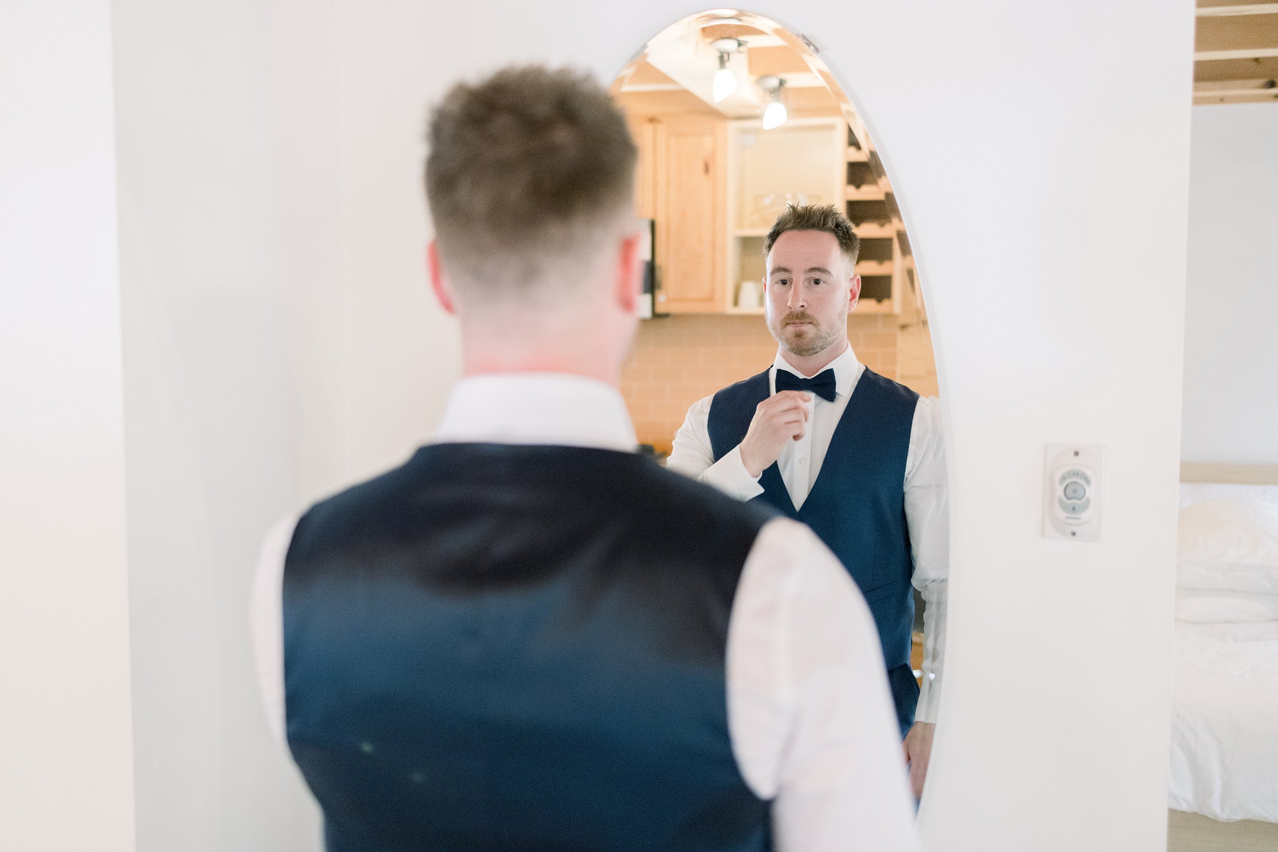  The groom straightens his bowtie in the mirror while getting ready by Chelsea Mason Photography. the groom gets ready wakefield wedding #ChelseaMasonPhotography #ChelseaMasonWeddings #WakefieldWeddings #LeBelvedere #Wakefieldweddingphotographers 