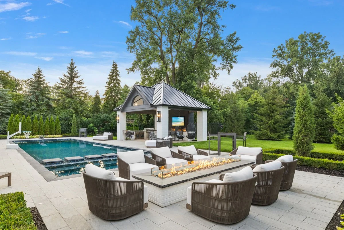 elegant rectangular gunite pool and spa are central to this luxury outdoor living space with custom pavilion, outdoor kitchen and fireside lounge