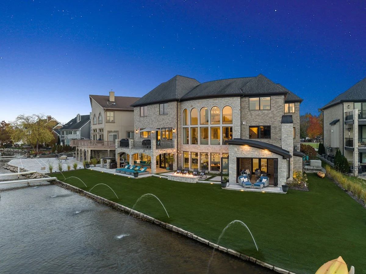 A lakeside home with an expansive outdoor living space including a balcony, covered patio, fireside lounge and four seasons lanai