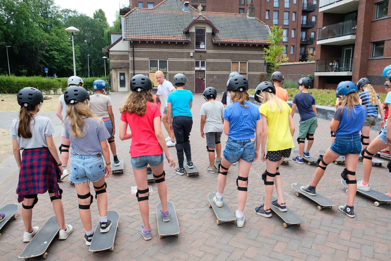 De skateleraar legt de oefening uit aan een groep leerlingen