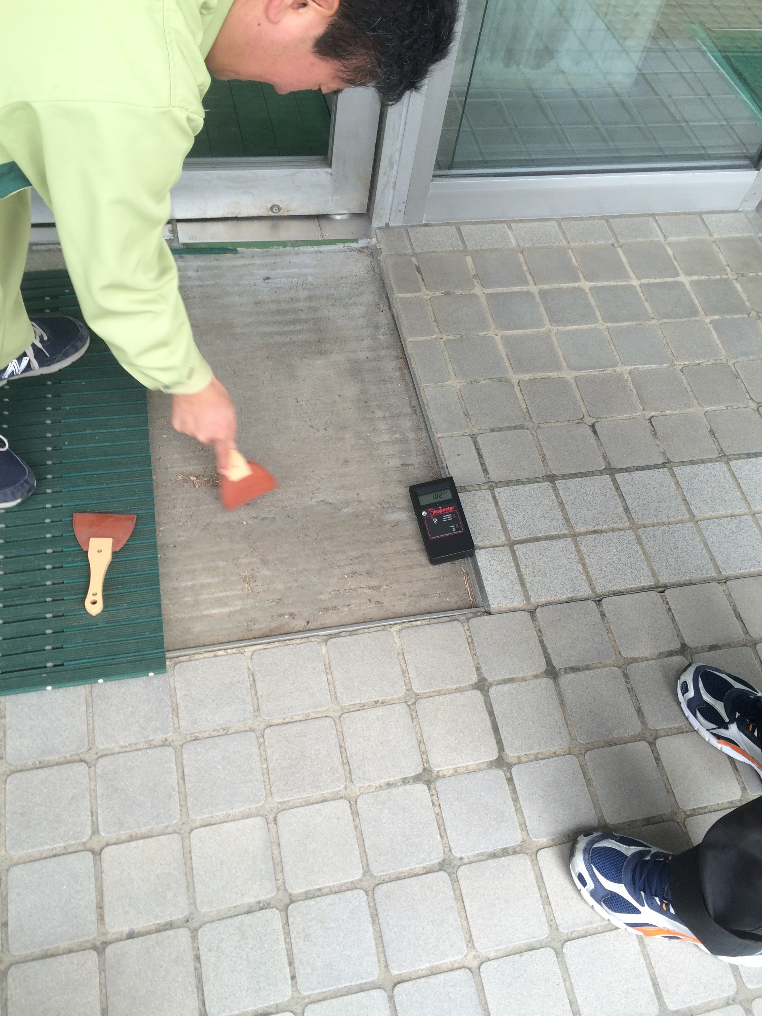 Taking dust samples underneath floor matts at a convenience store. Proves radiation is being spread everywhere.