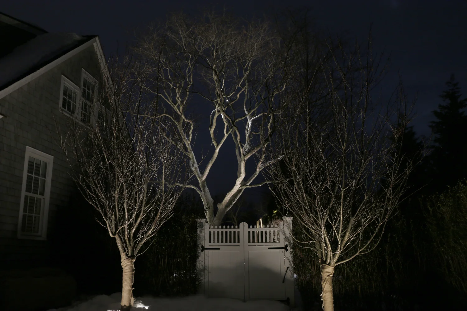 Side elevation lighting at Watermill luxury estate — wall wash and uplighting on home architecture at night