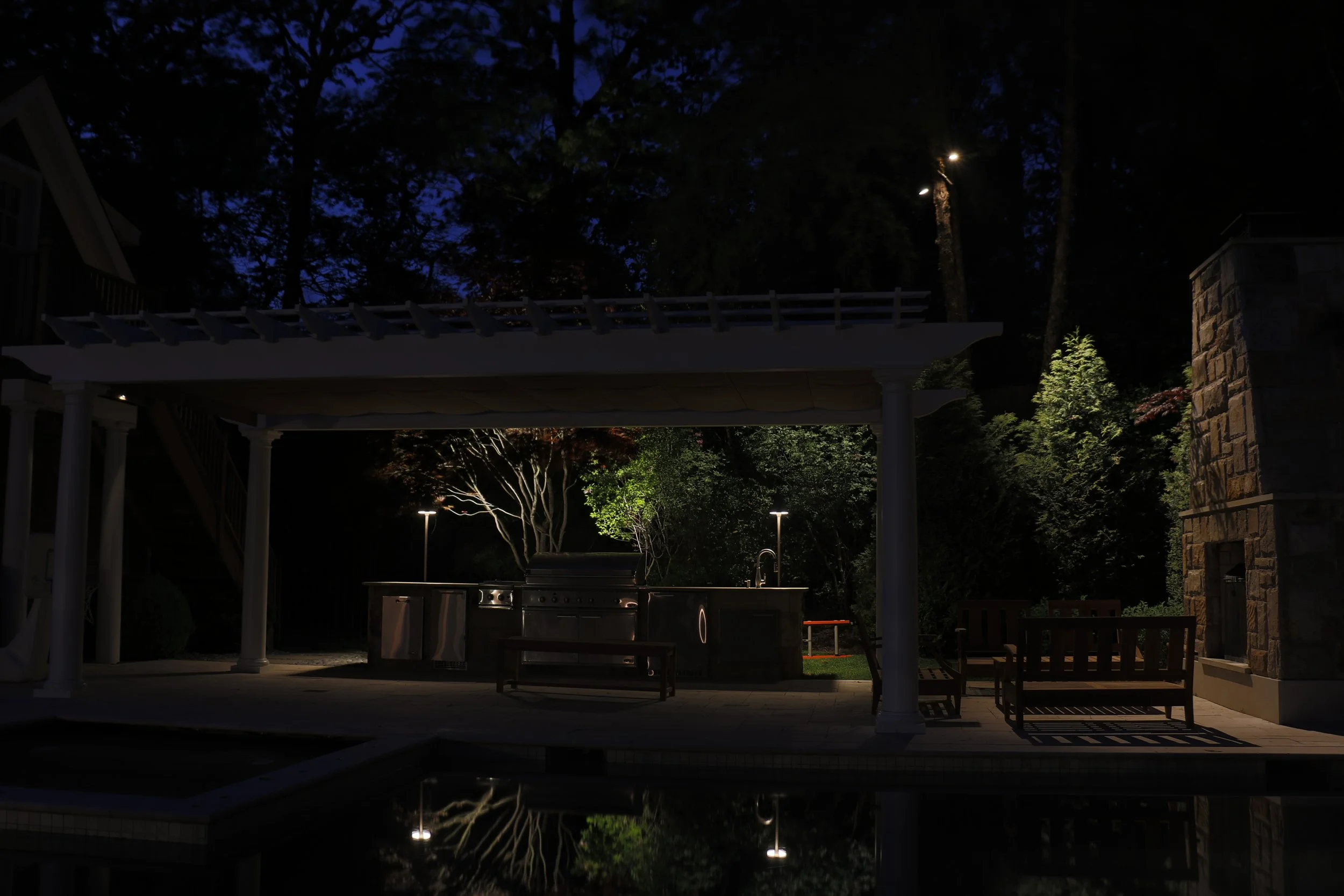 Outdoor kitchen and covered entertainment area illuminated at night