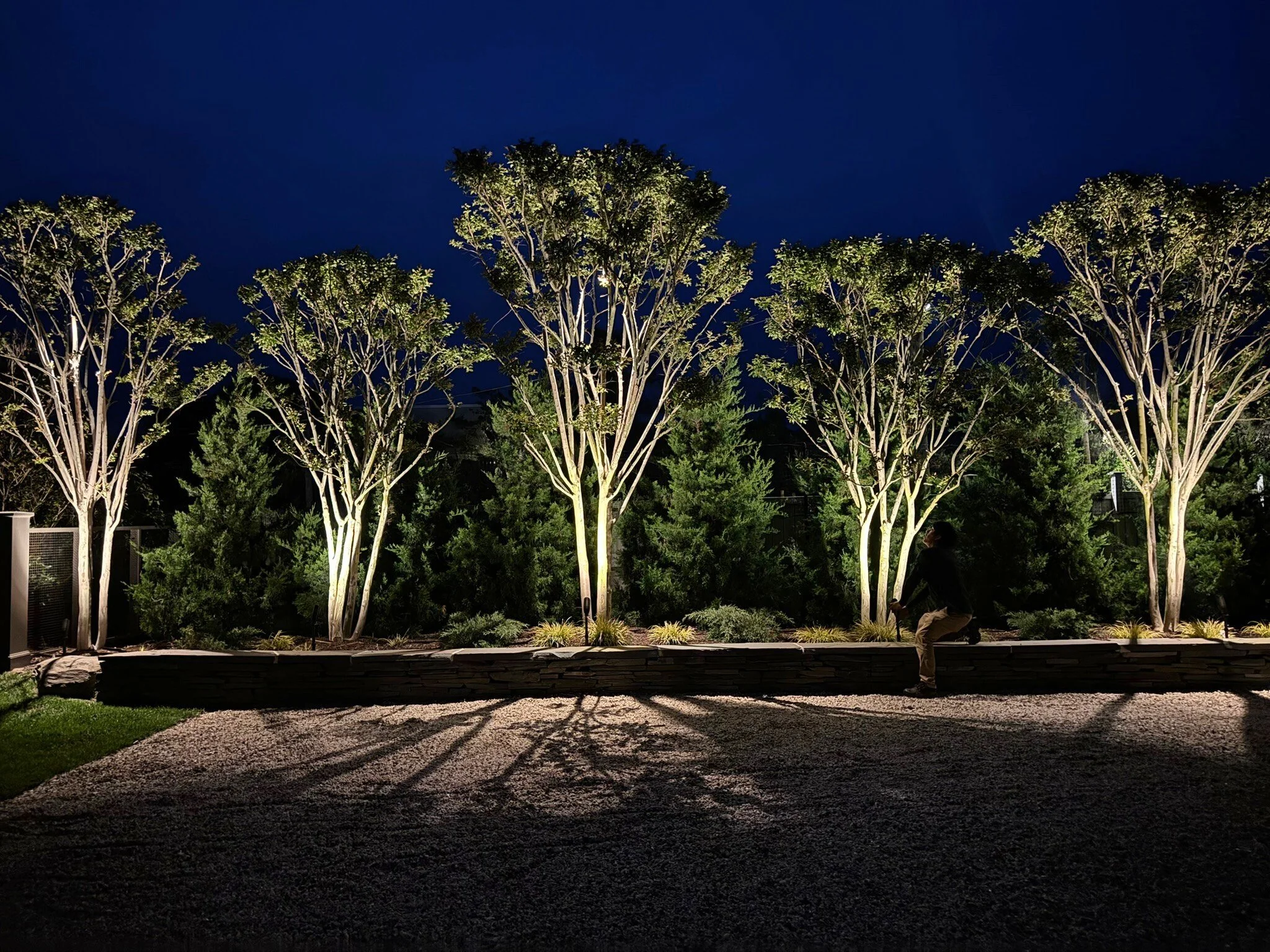 Night aiming service by Hamptons Landscape Lighting — technician re-aiming landscape fixtures after dark at Westhampton estate