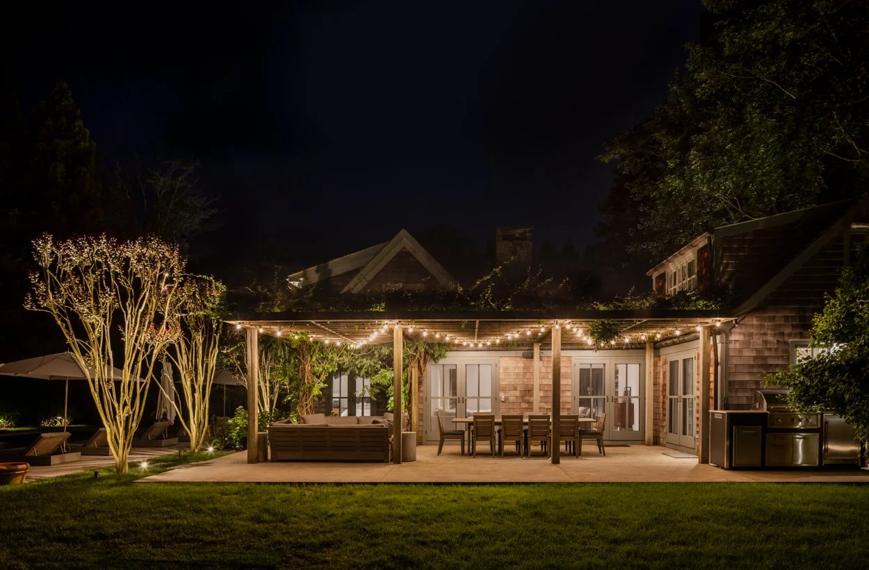 Lit garden path at Amagansett estate — pathway lighting through manicured Hamptons garden at night