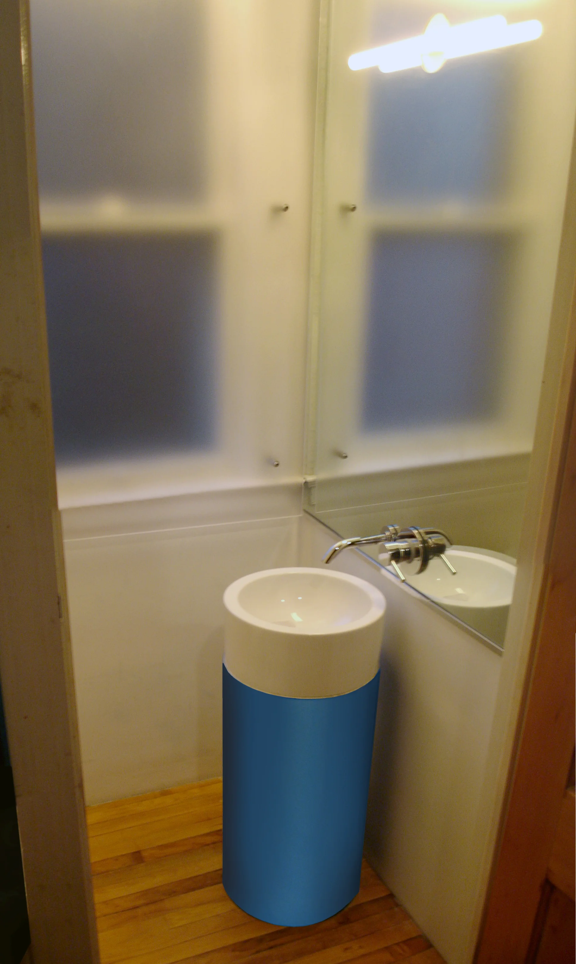 Designed for a residential client, the brightly colored pedestal sink and large mirror give a greater sense of space and movement in the small room.