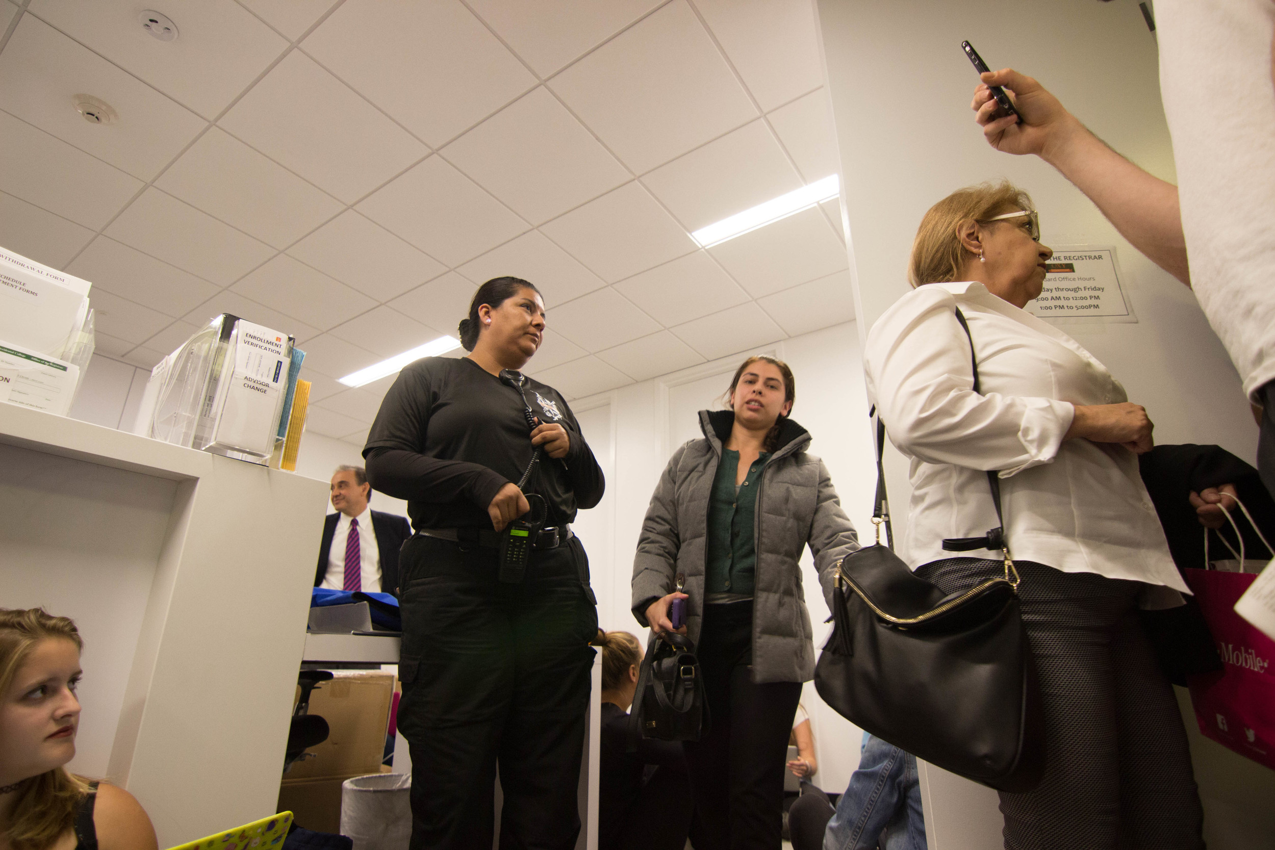 Two employees from the College Registrar are escorted by a Campus Safety officer from their occupied office. 