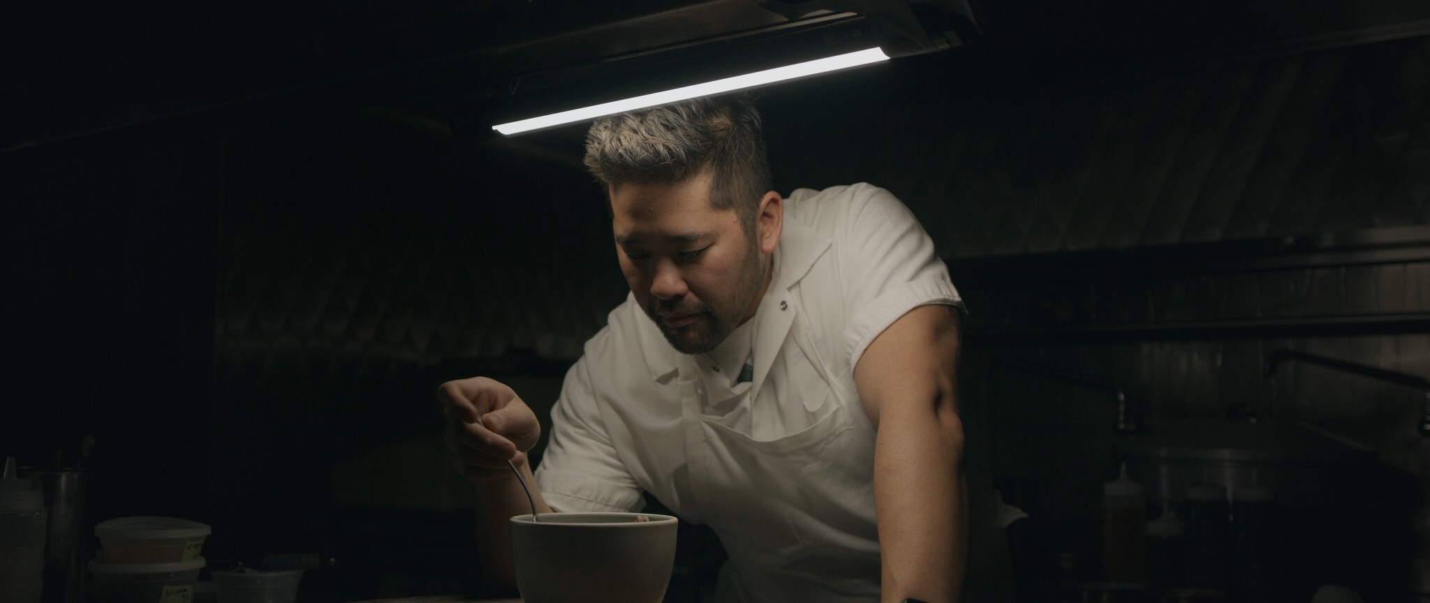  chef Brandon Jew tasting a dish. cinematography by Austin Straub for The Migrant Kitchen. 