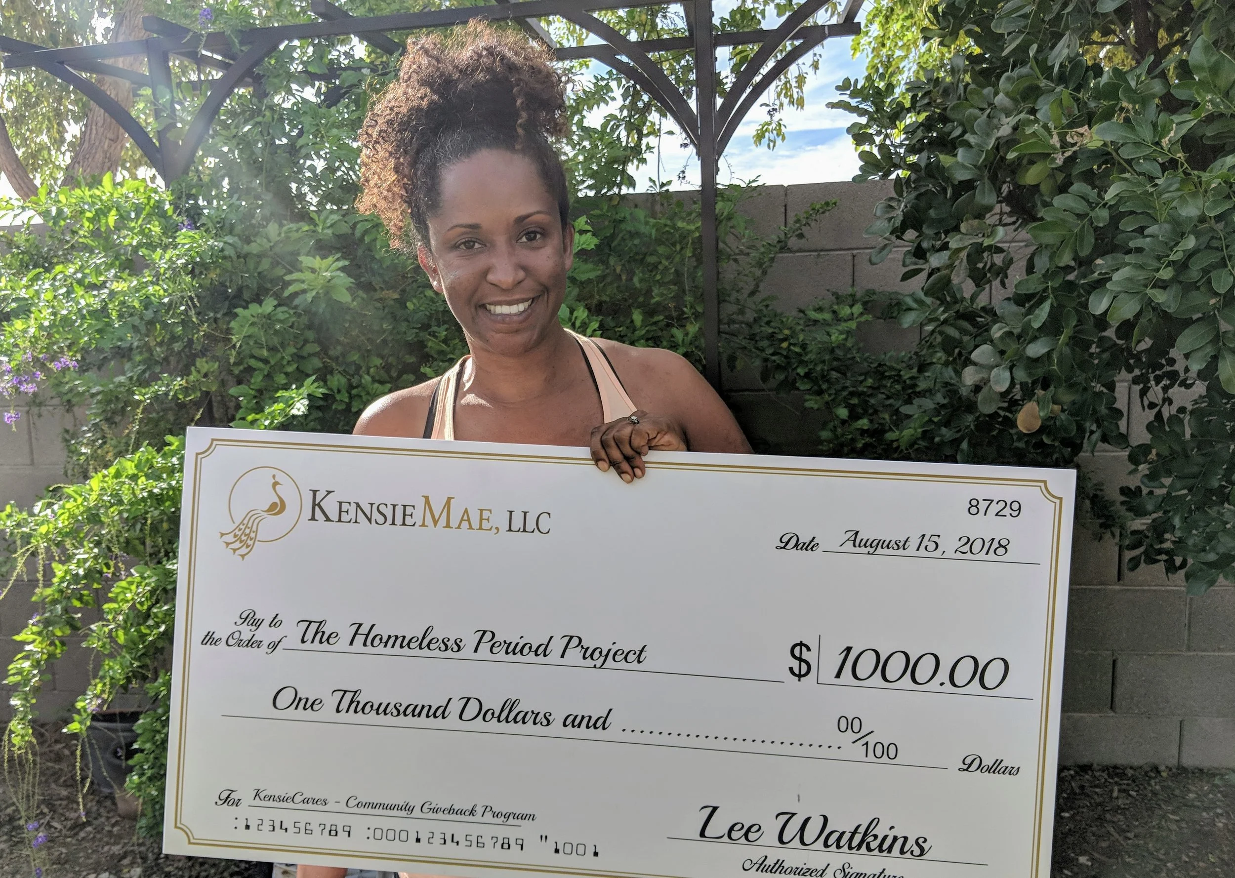 Ona Watkins, HPP - Phoenix Chapter Branch Manager, Holds the donation being Made on behalf of KensieMae employee Lee Watkins for The Homeless Period Project.