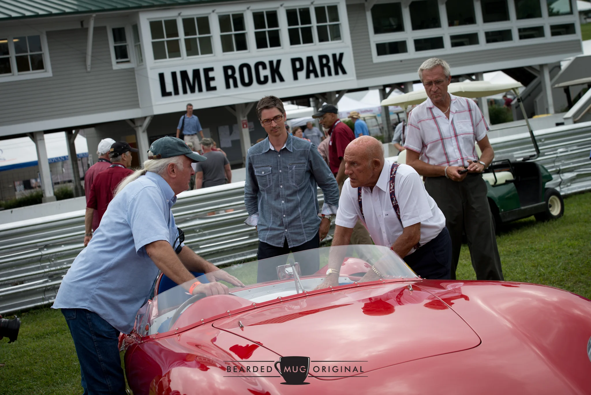 Meeting of the minds: Bruce from Redline Restorations talks shop with Sir Stirling Moss over the Maserati 300S, all the while author and illustrator Dwight Knowlton listens intently.